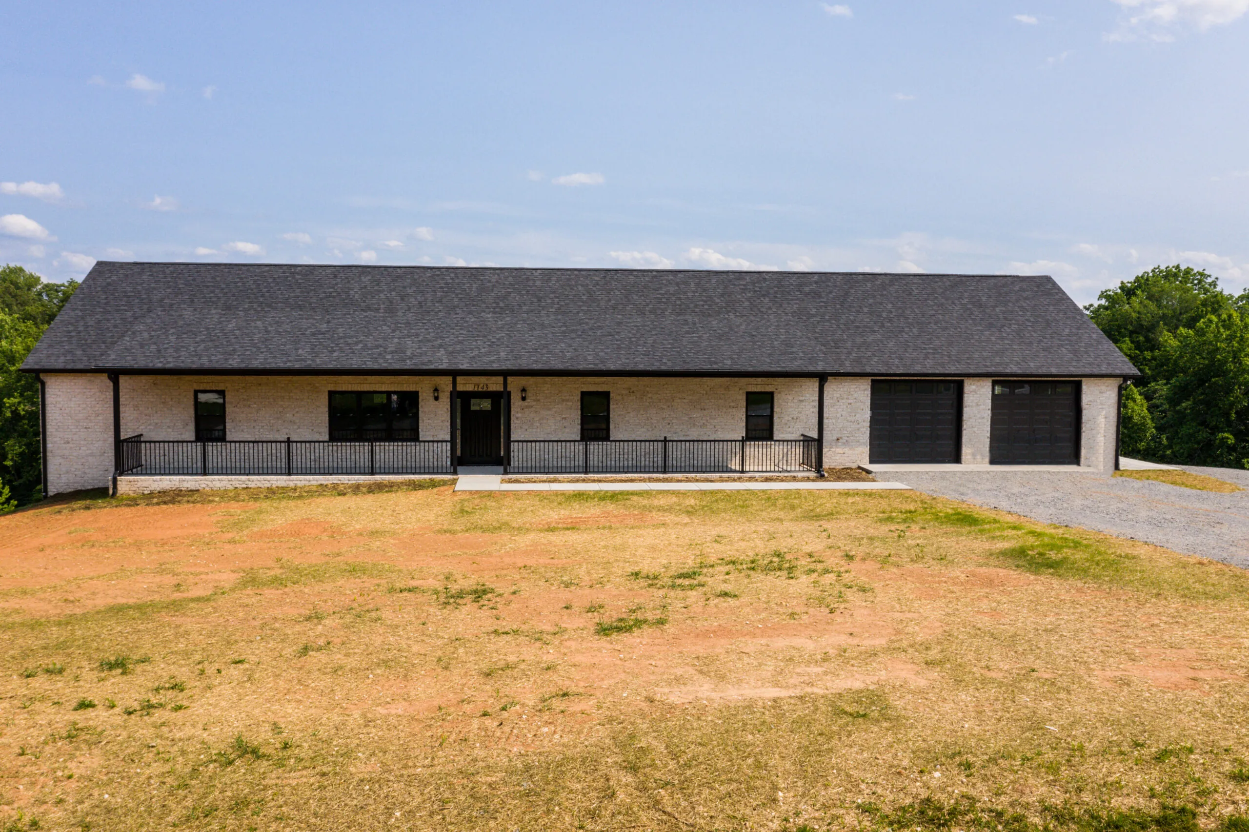 Front of the single-level brick Otterlea Home with covered porch and two-car garage