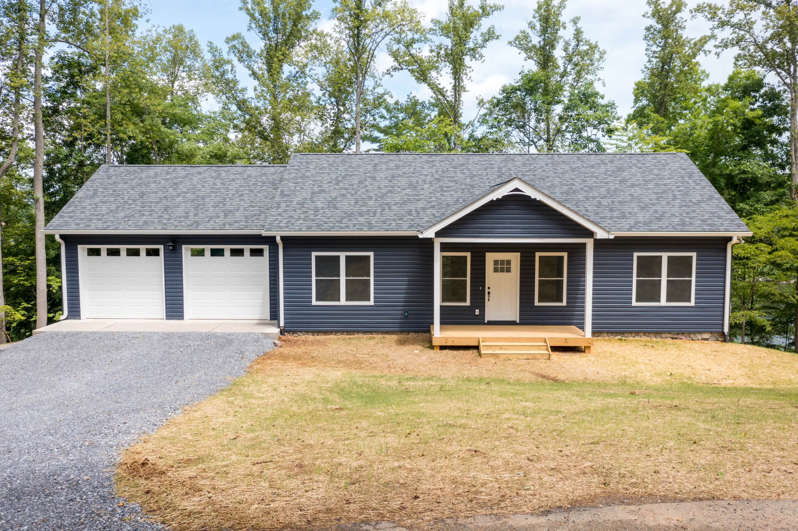 Front of the Lake Crest Home with navy siding, two garage doors and covered entry