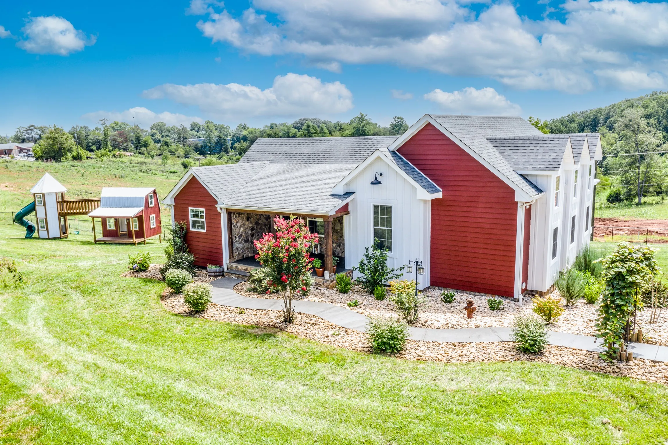 Aerial front view of the Lowry Home with red and white siding and stone porch