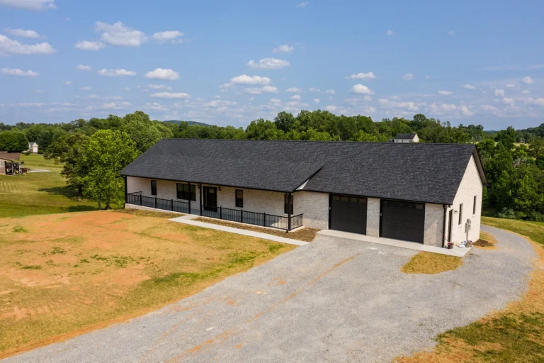 Spacious white brick rancher with a black shingle roof, black windows, and black gutters.