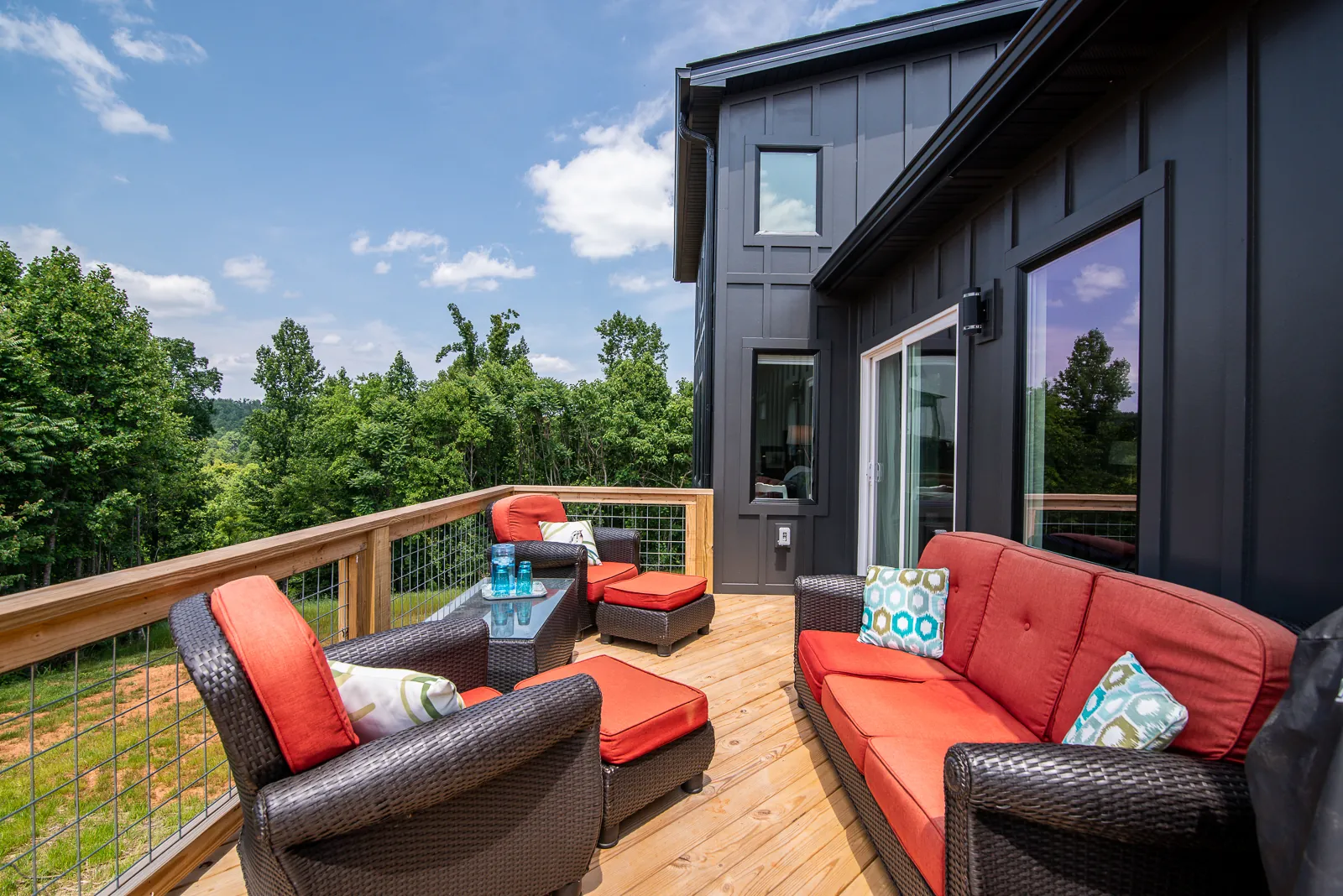 Wood deck with outdoor seating beside the dark board-and-batten siding of the LynBrook Home