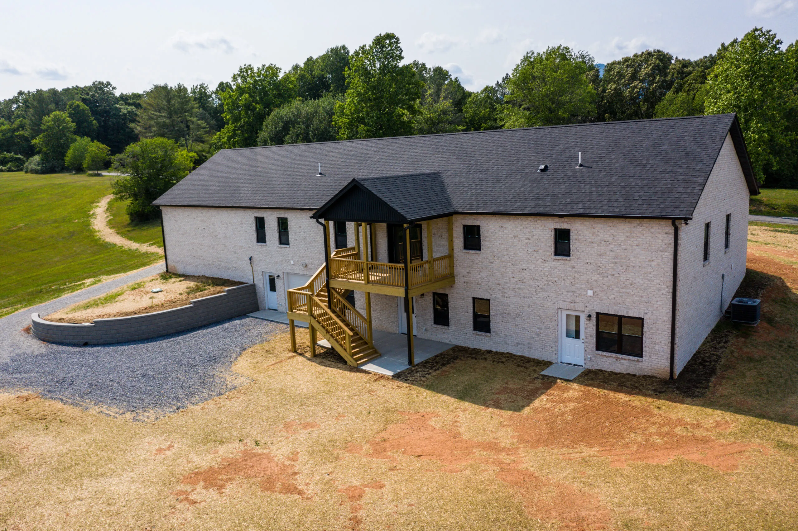 Rear of the brick Otterlea Home with gravel drive and upper deck