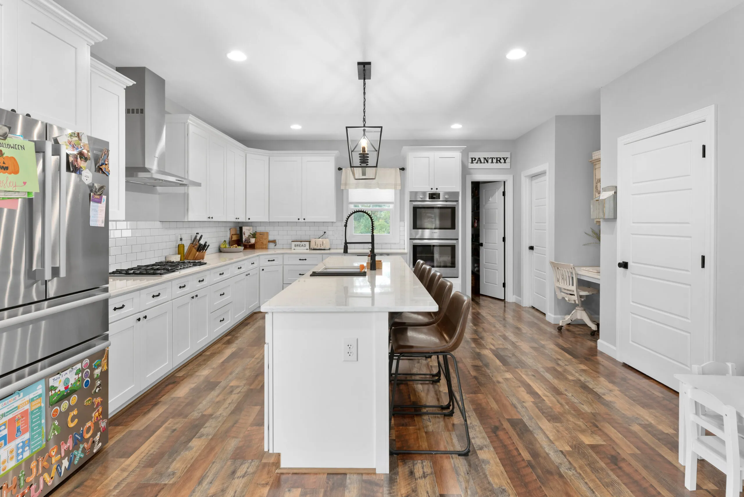Kitchen in the Peters Creek Home with white cabinets, large island and double wall ovens