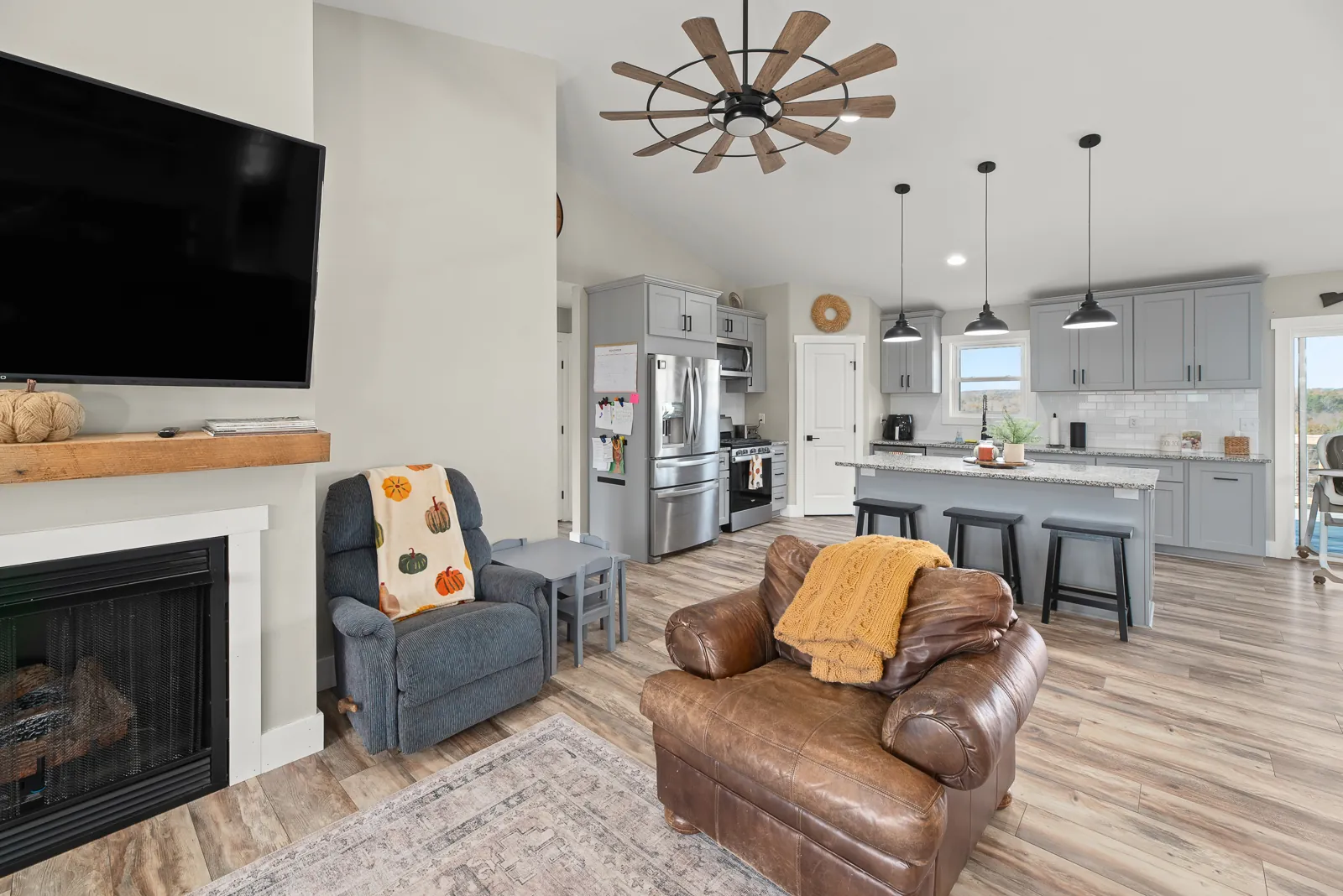 Living room with gas fireplace opening to the kitchen in the Carter's Mill Home
