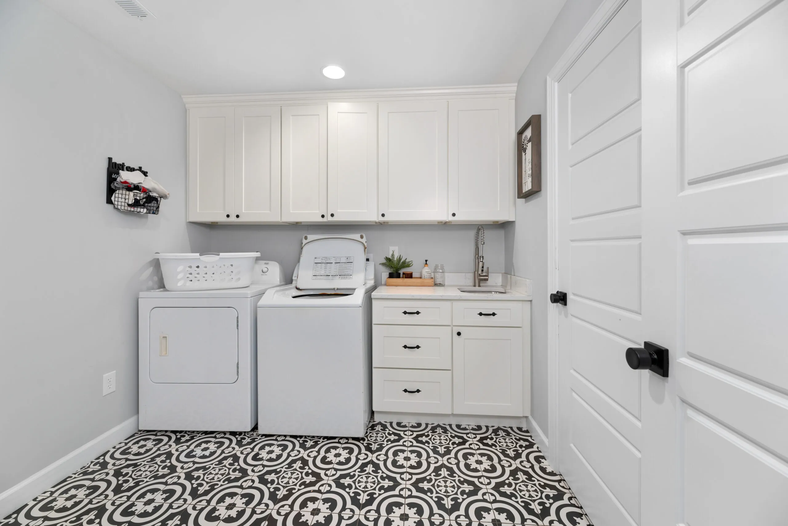 Laundry room with white cabinets and patterned tile floor in the Peters Creek Home