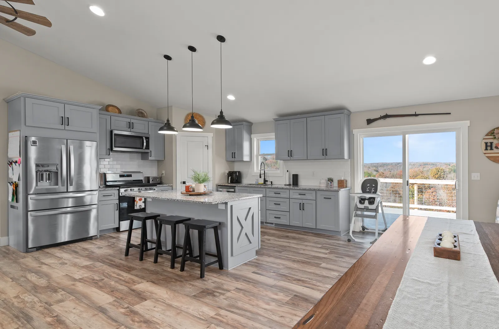 Kitchen with gray cabinets and island opening to a deck view in the Carter's Mill Home