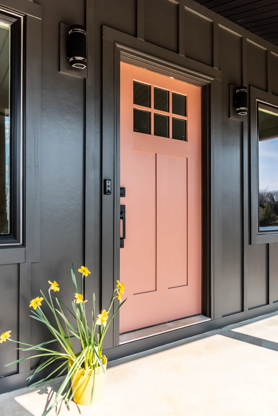 Coral front door on dark board-and-batten siding at the LynBrook Home