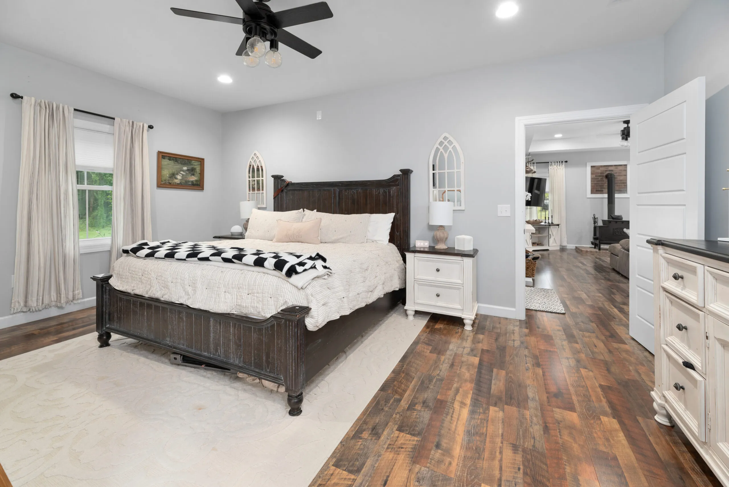 Primary bedroom with dark wood bed and open doorway to living area in the Peters Creek Home