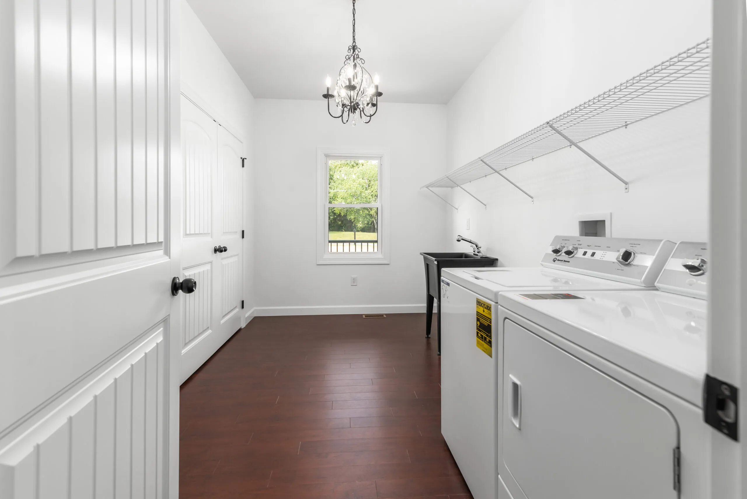 Laundry room with chandelier, wire shelving and window in the Otterlea Home