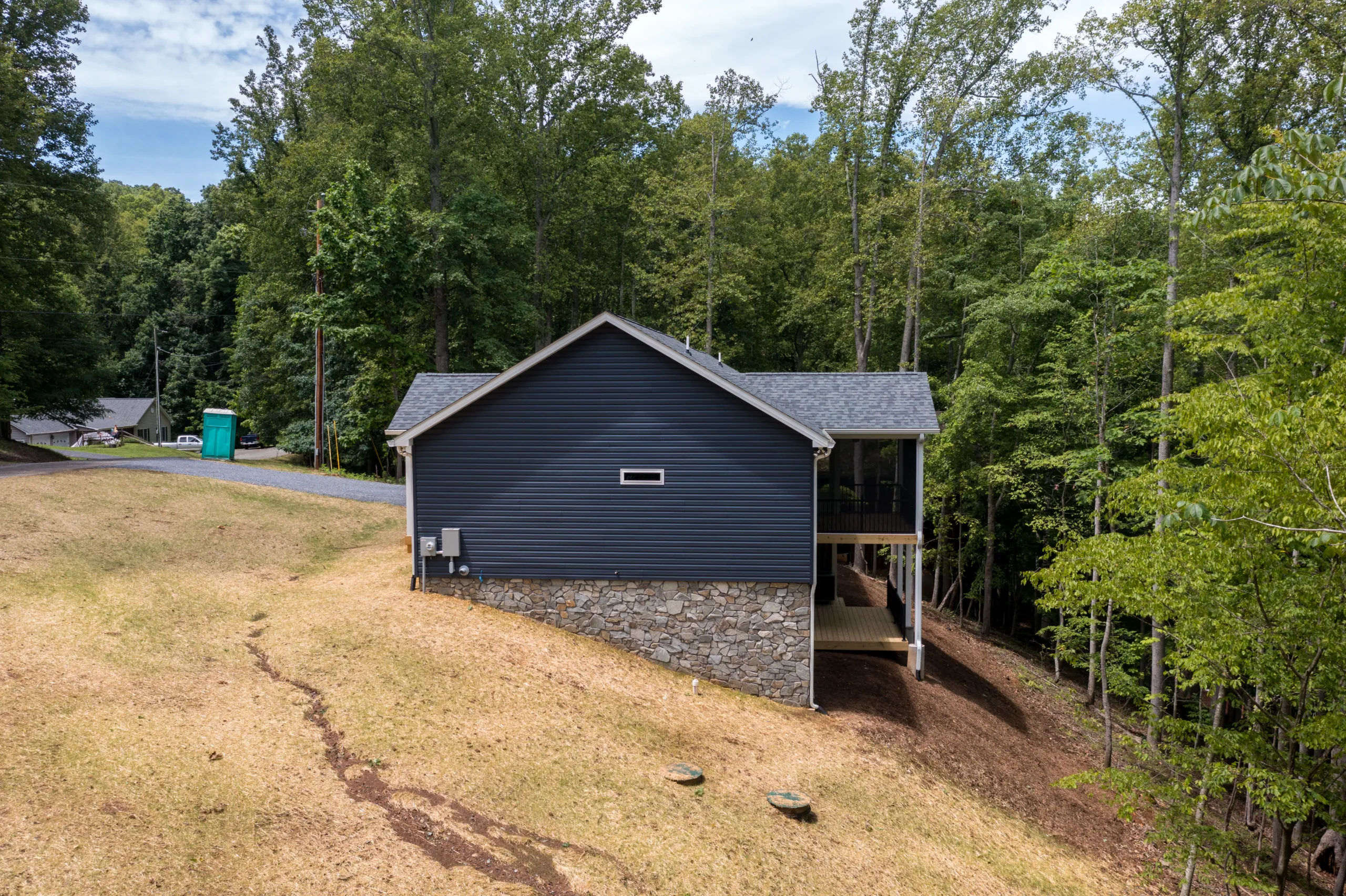 Right side of the Lake Crest Home with navy siding and stone foundation