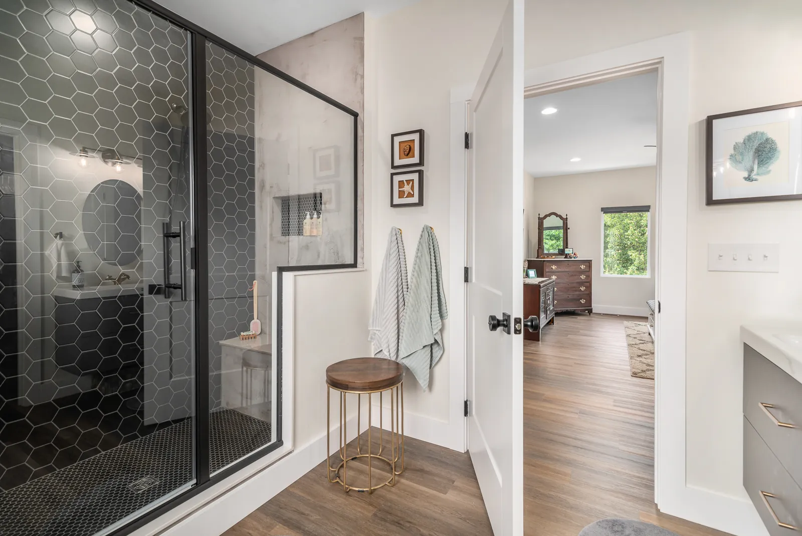 Primary bathroom with black hex-tile shower and glass enclosure in the LynBrook Home