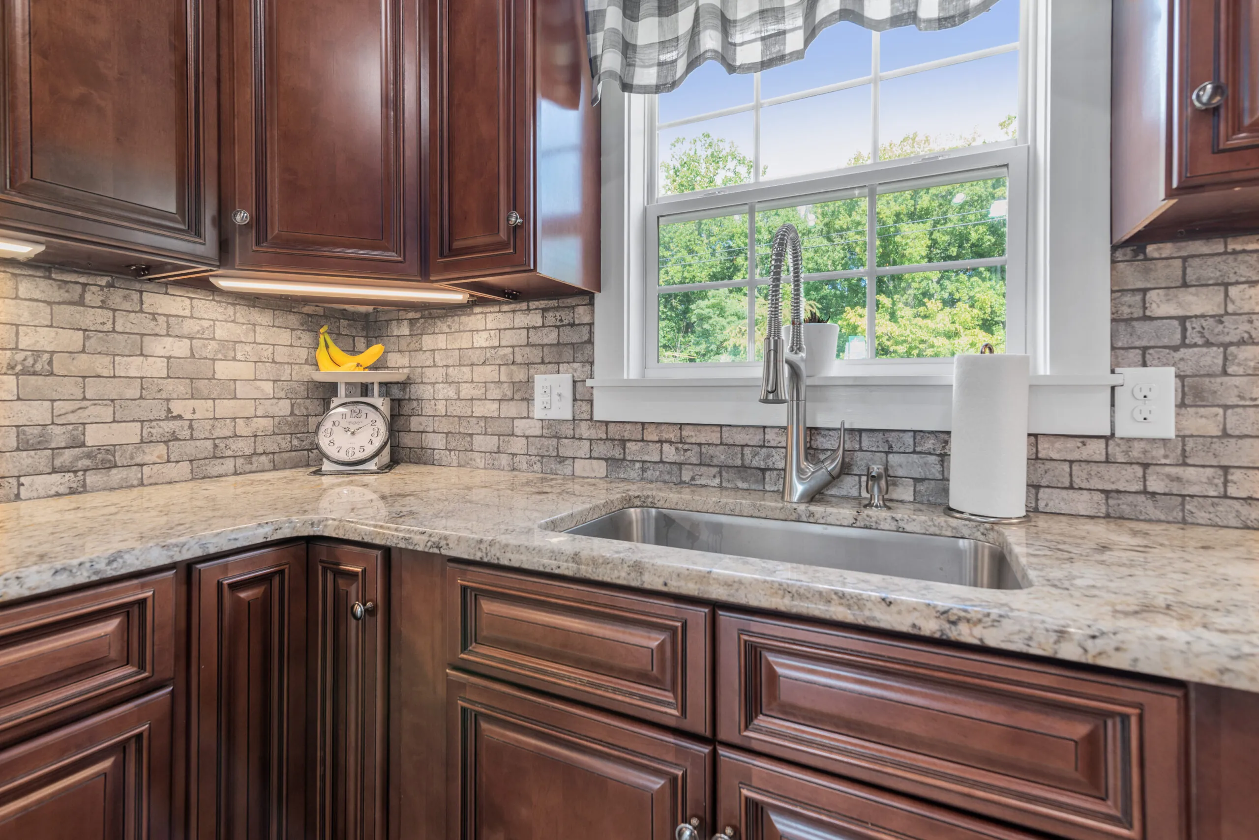 Kitchen sink with brick backsplash and cherry cabinets in the Lowry Home