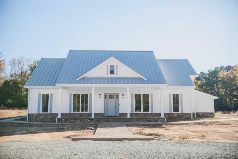 Front of the Java Home with white siding, blue metal roof and covered porch