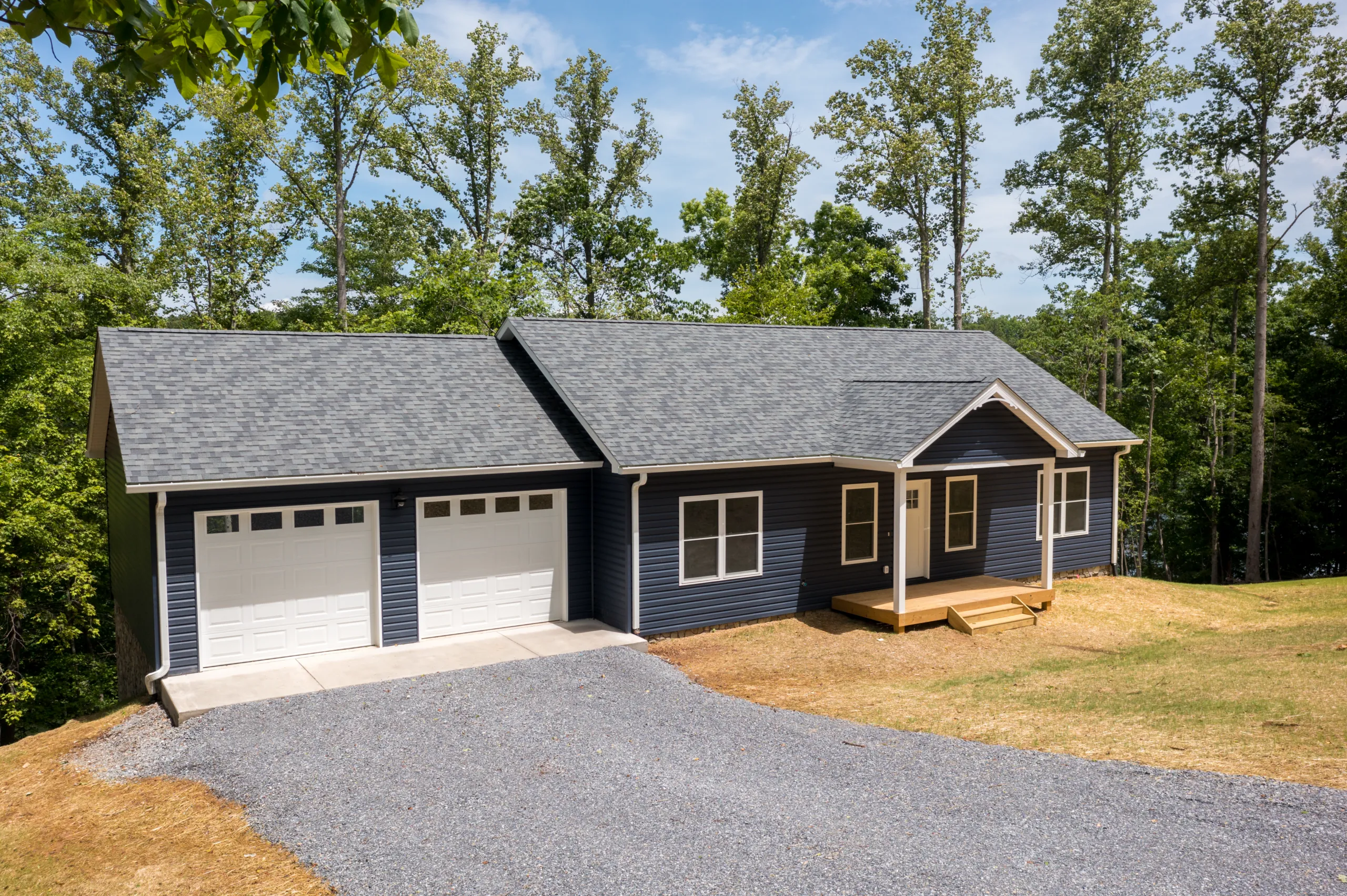 Angled front view of the Lake Crest Home with attached two-car garage and gravel drive