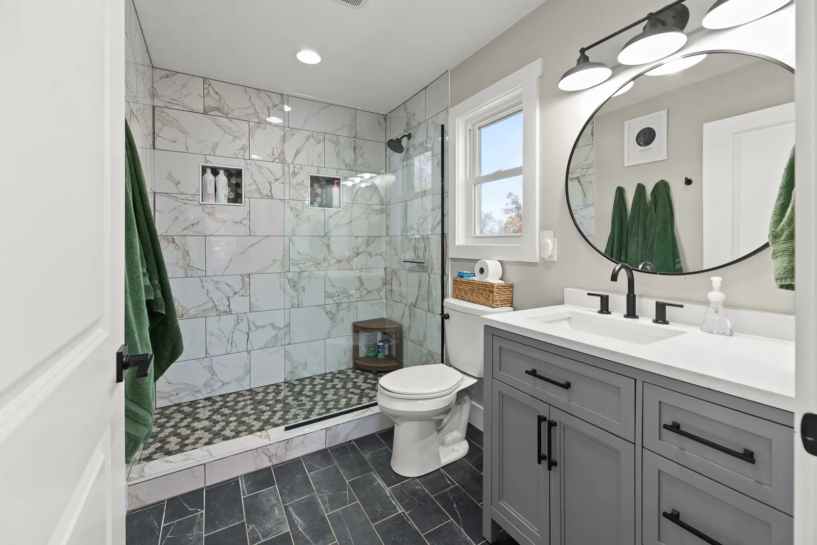 Primary bathroom with tiled walk-in shower and gray vanity in the Carter's Mill Home