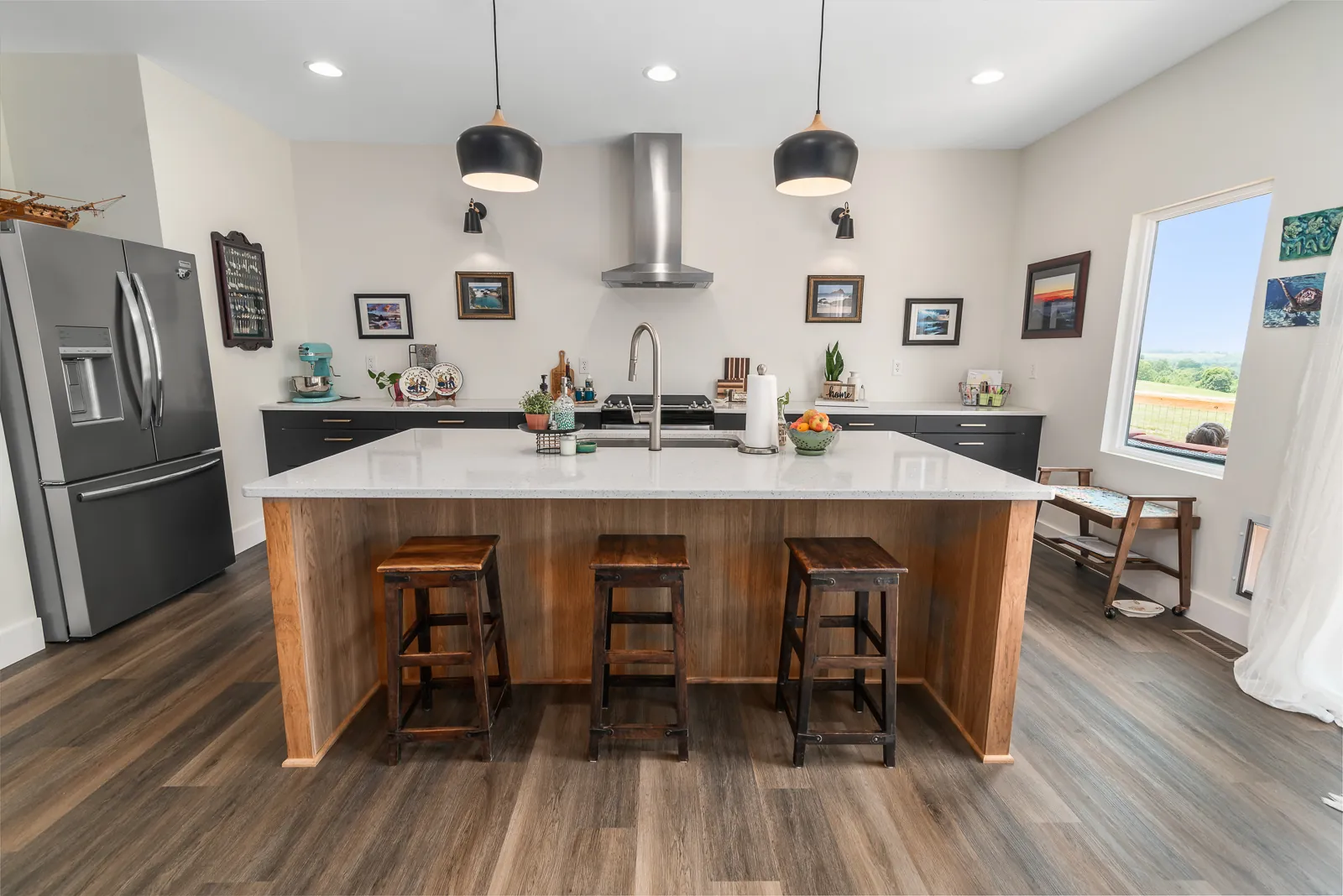 Kitchen island with white countertop, pendants and range hood in the LynBrook Home