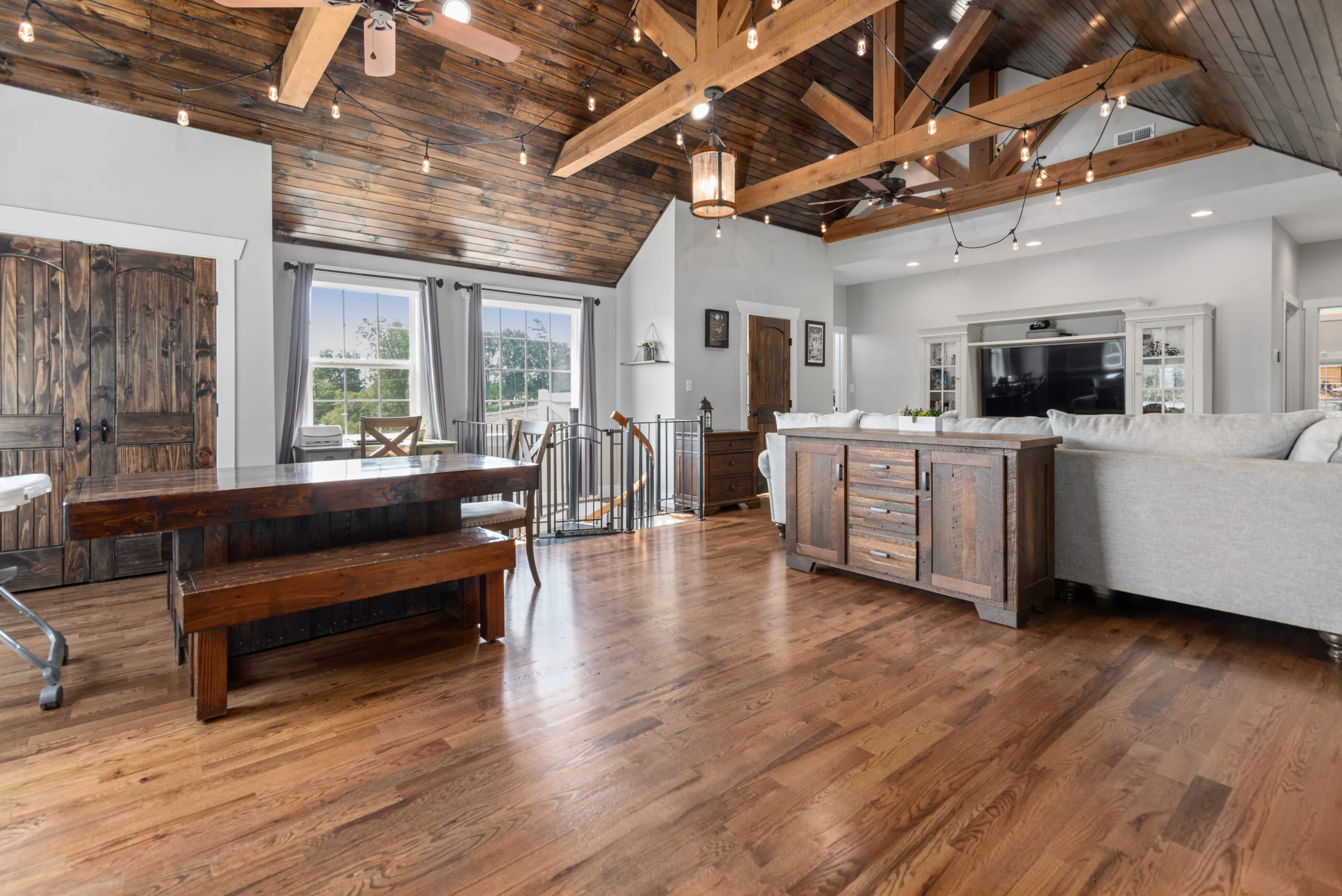 Open dining and living area with exposed beams and wood ceiling in the Lowry Home