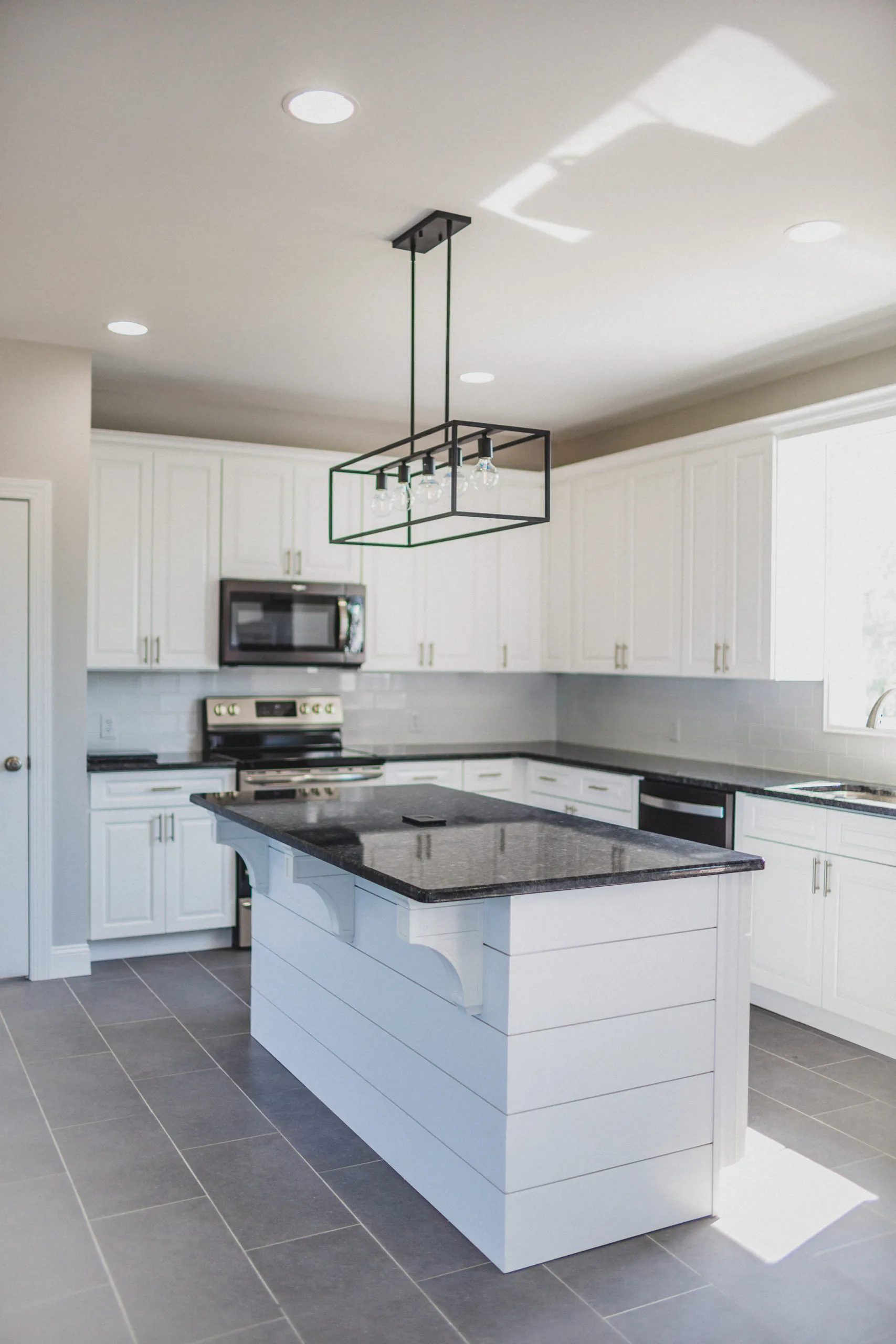 Kitchen island with granite top and black pendant light in the Falling Creek Home