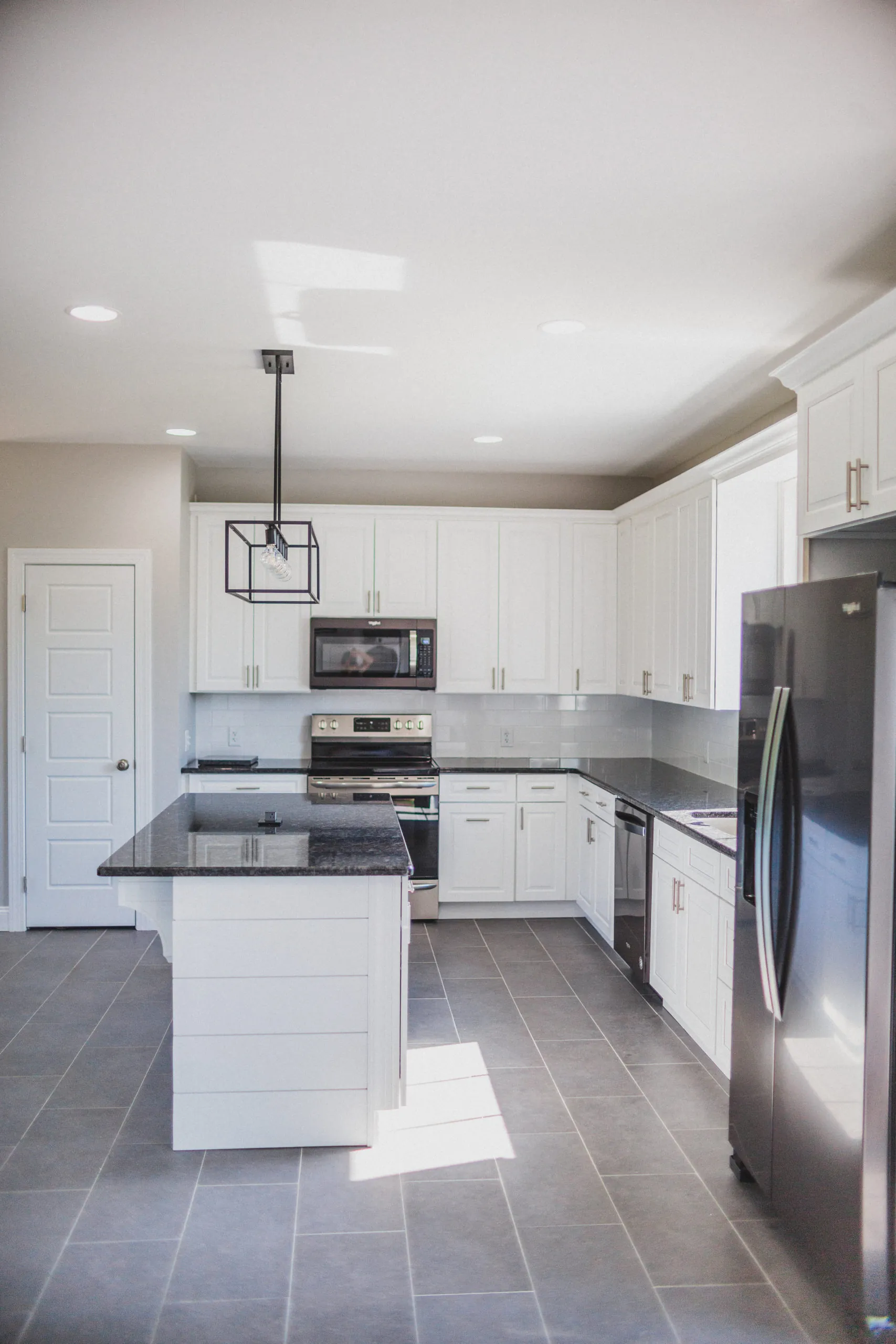 White kitchen with granite counters and shiplap island in the Falling Creek Home