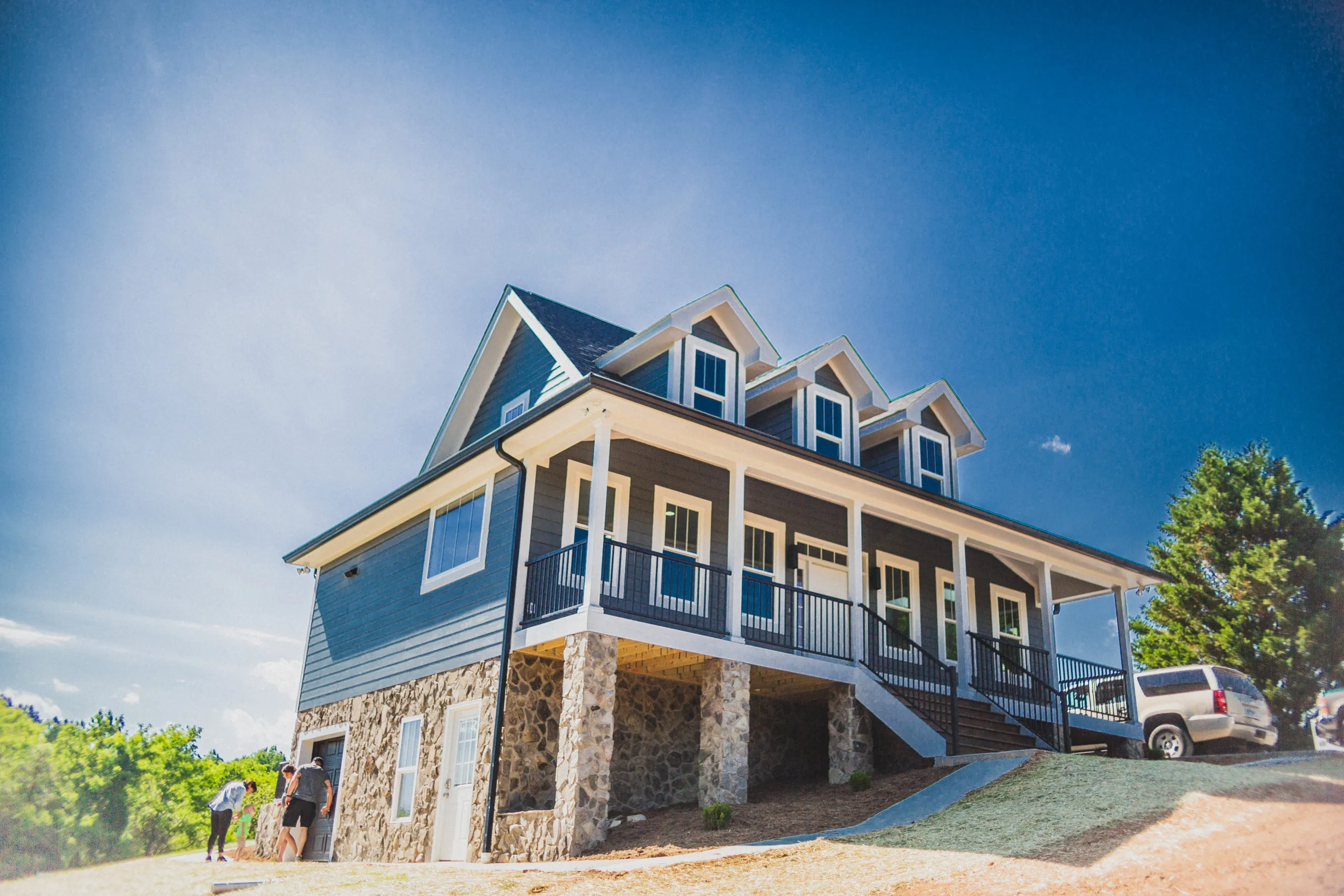Exterior of the Falling Creek Home with covered wraparound porch and stone base