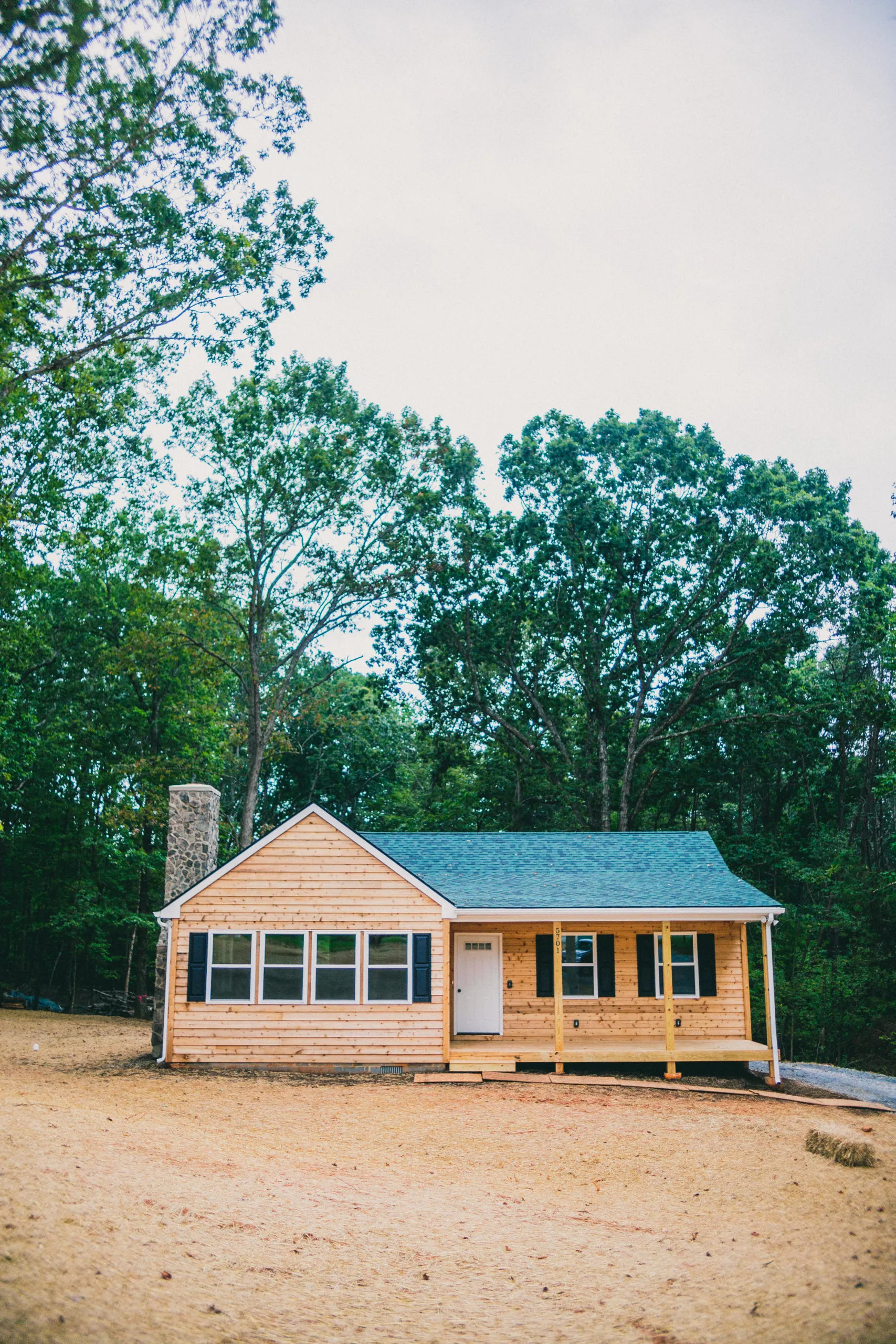 Front exterior of the Forest Home with cedar siding, stone chimney and covered porch
