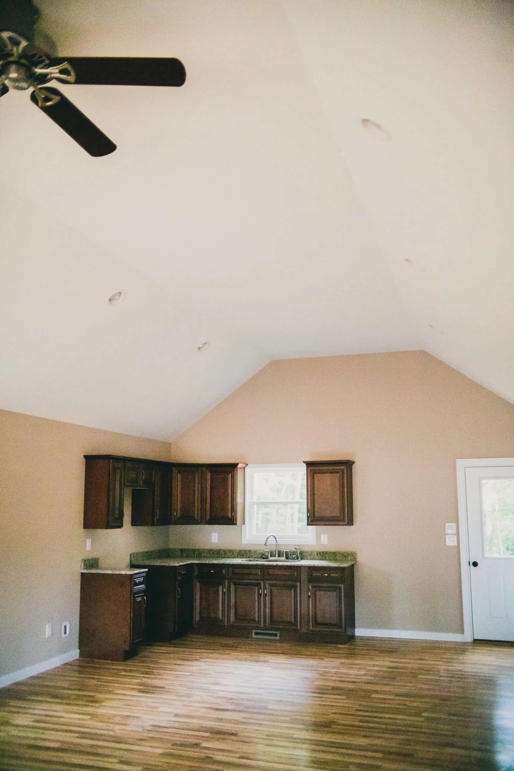 Vaulted open room with kitchenette cabinets and ceiling fan in the Forest Home