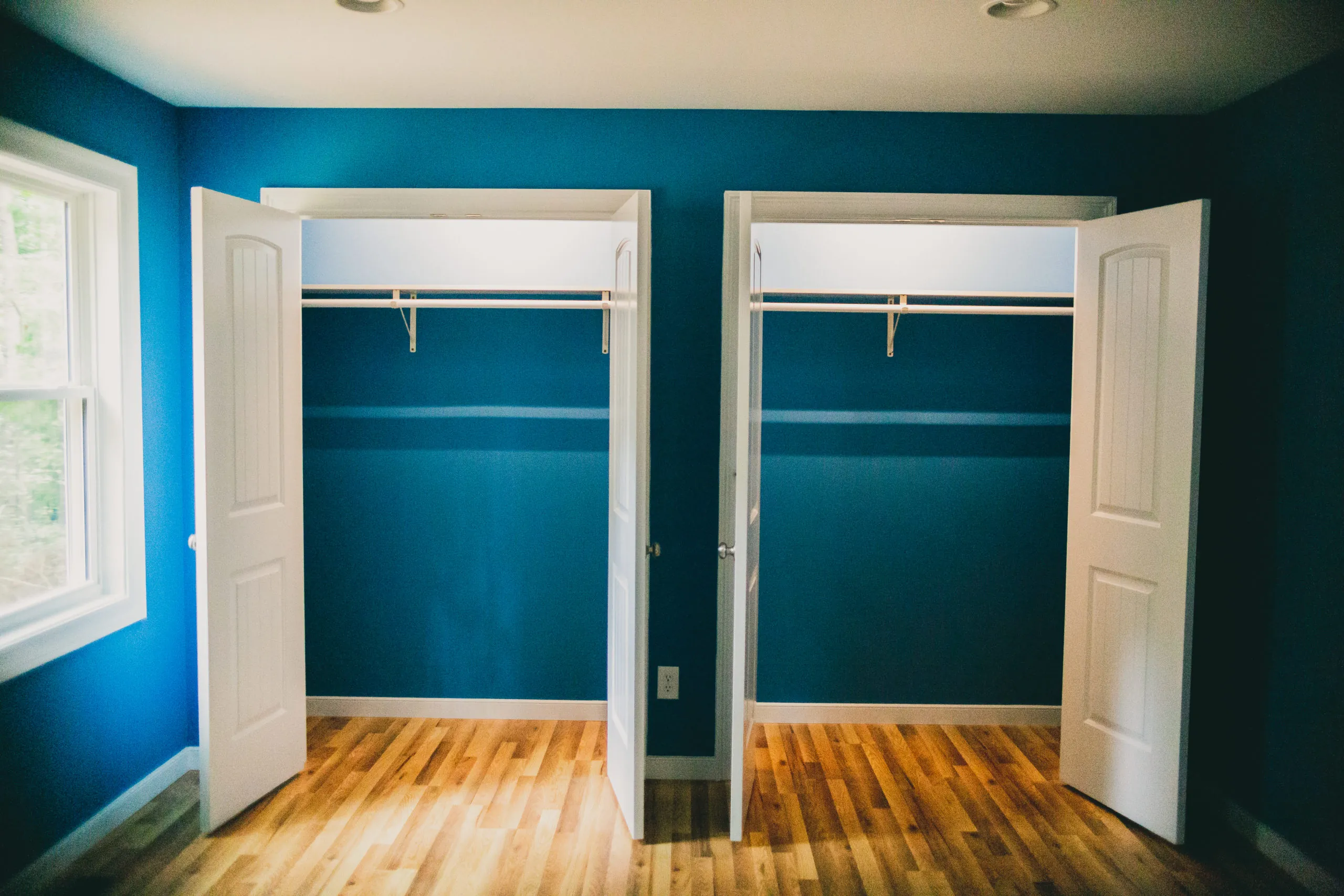 Bedroom closets with open doors and blue walls in the Forest Home