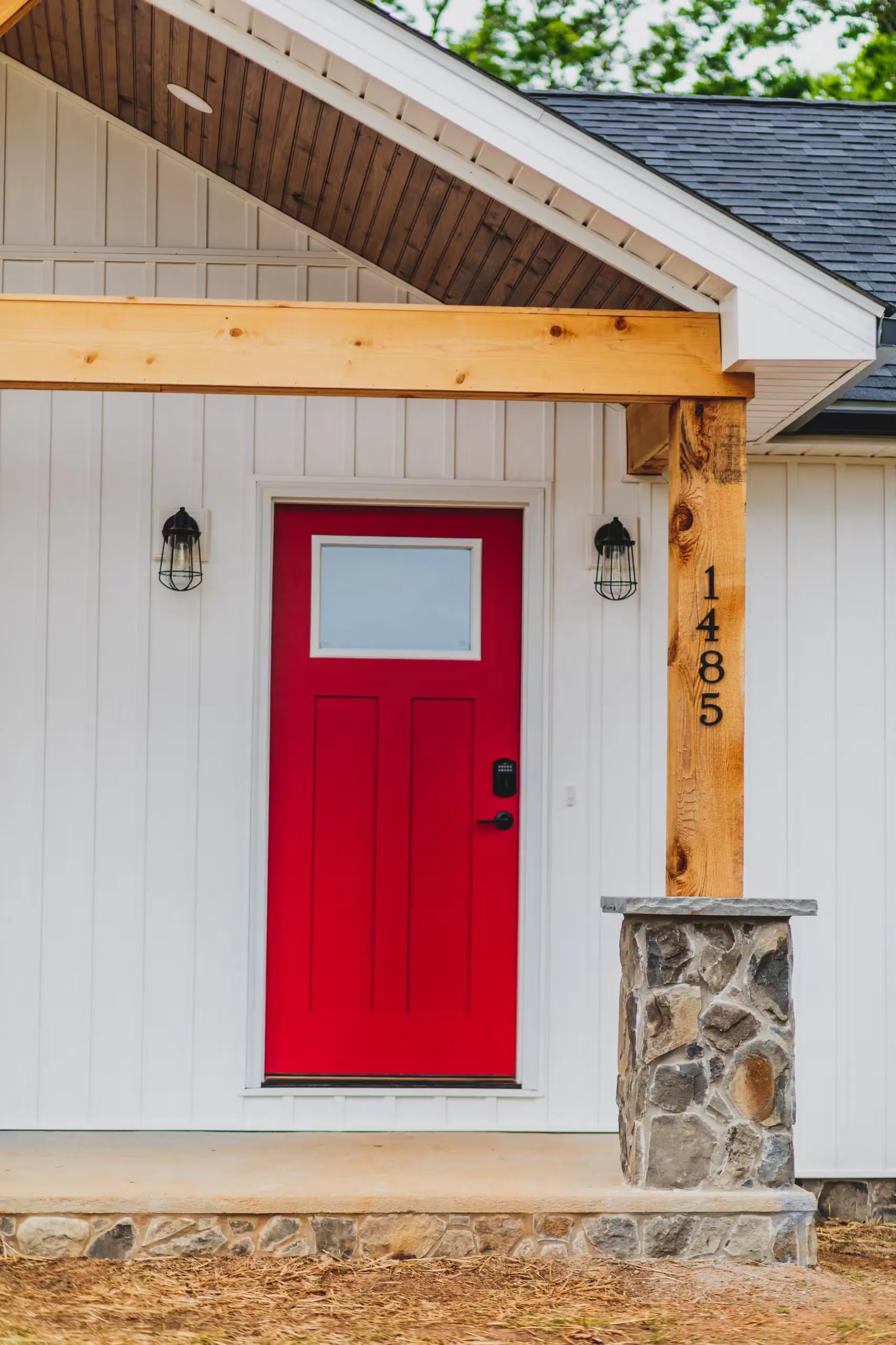 Red front door under a timber-framed porch at the Lake Cross Home