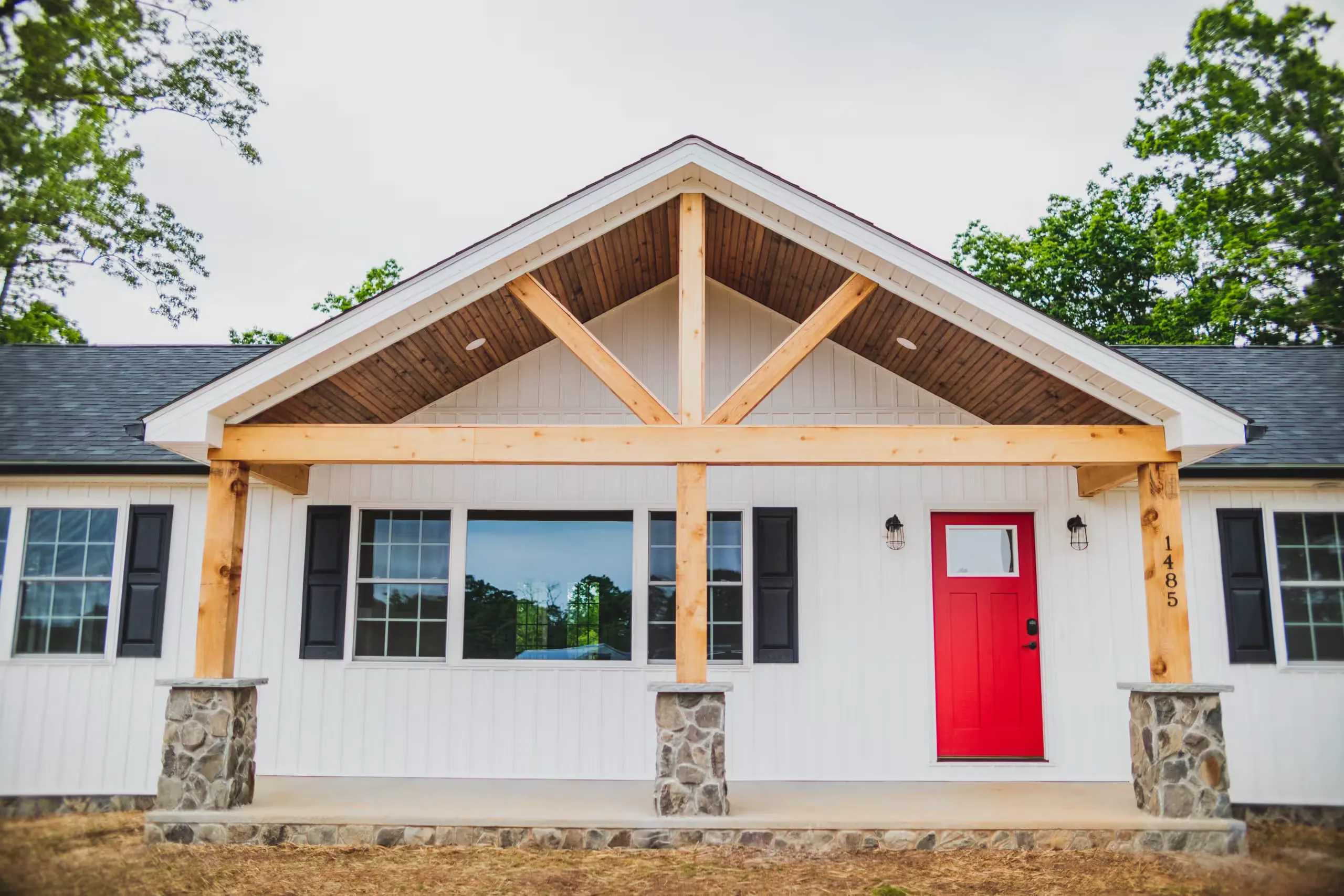 Front porch of the Lake Cross Home with timber gable, stone columns and red door