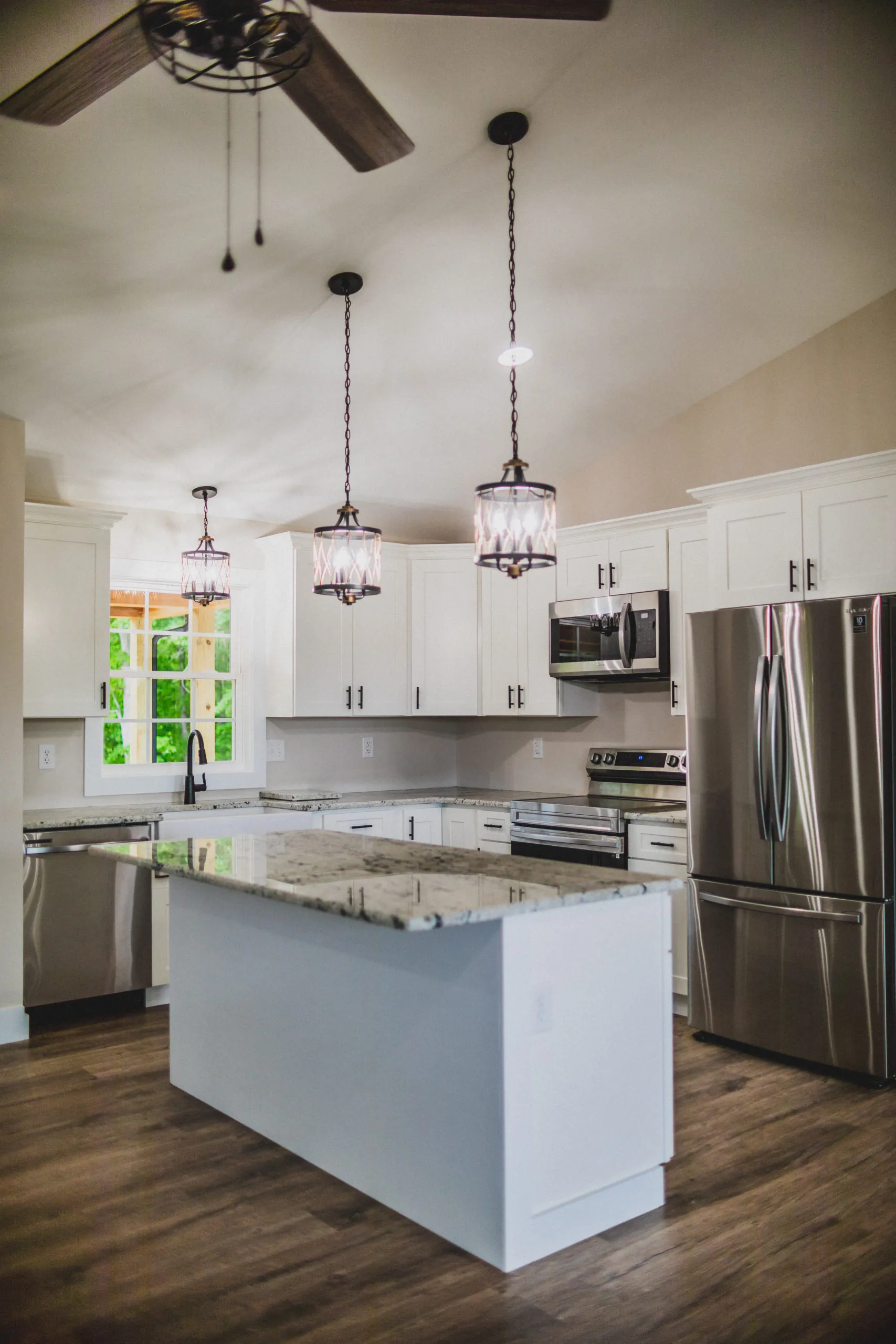 White shaker kitchen with granite island and pendant lights in the Lake Cross Home
