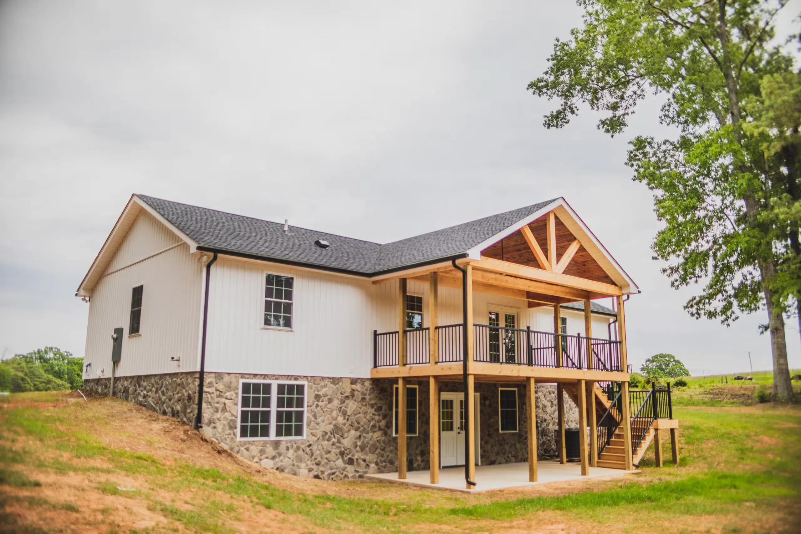 Rear corner of the Lake Cross Home with timber-framed deck gable and stone foundation