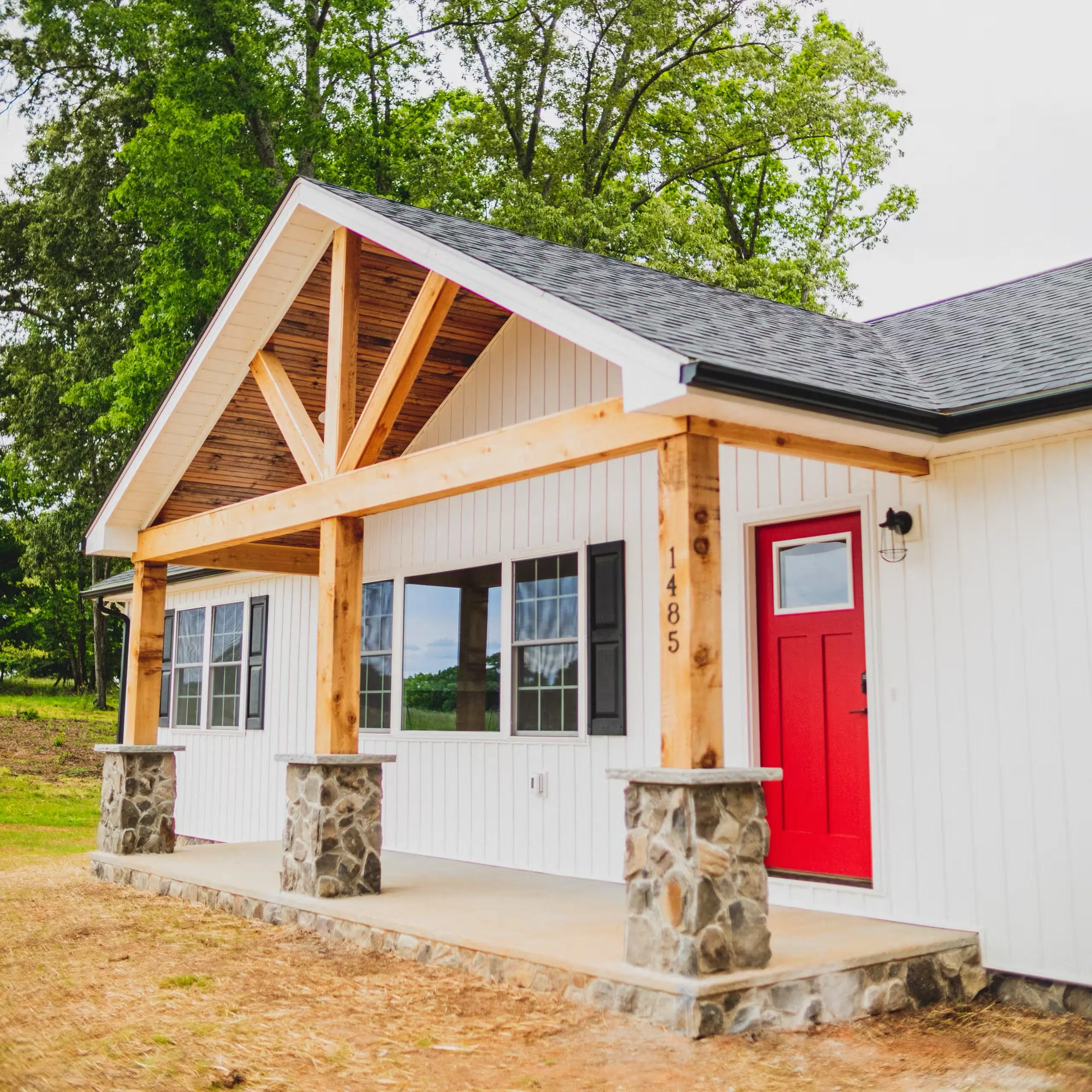 Angled view of the front porch of the Lake Cross Home with timber truss and stone piers