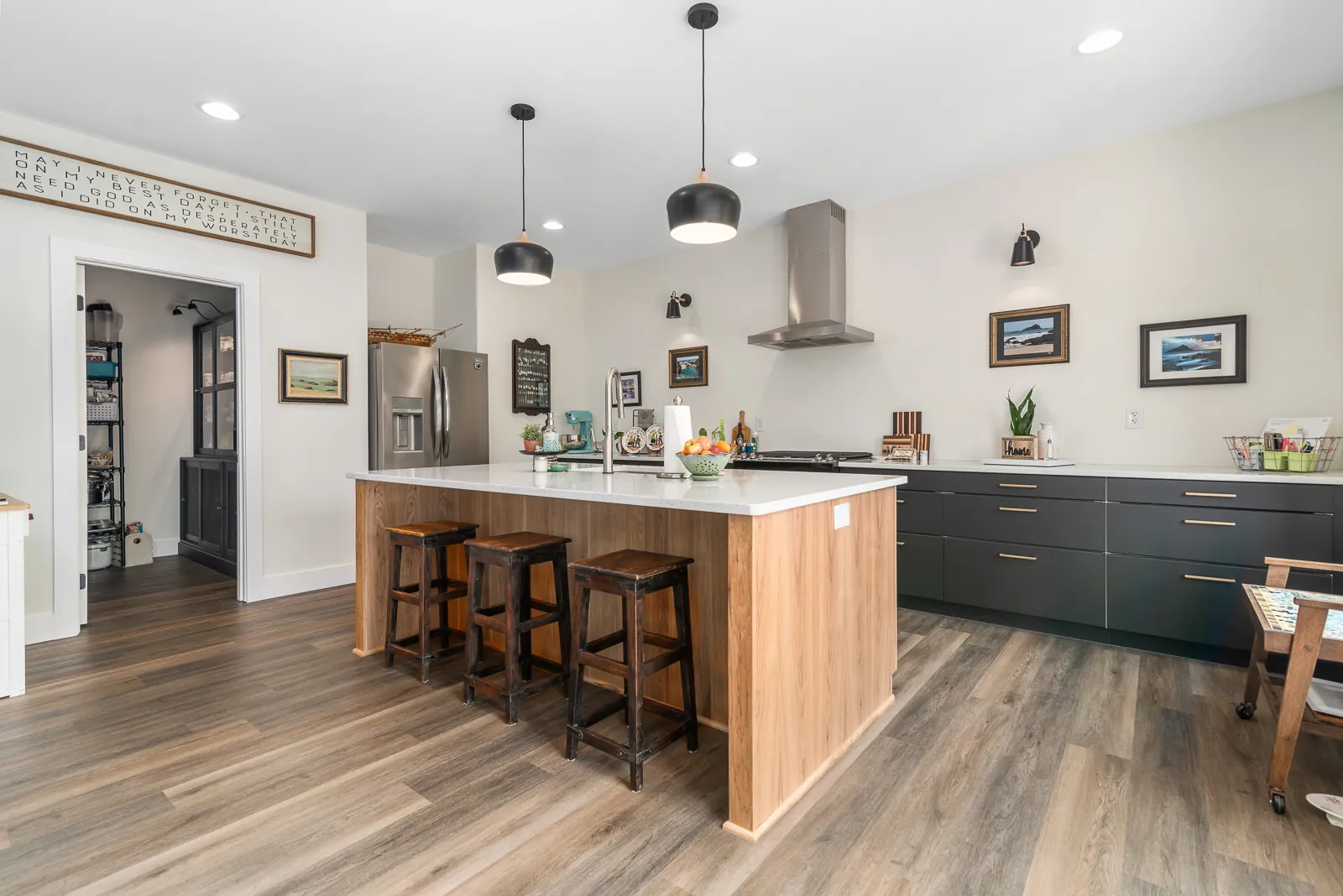 Kitchen island with bar stools and dark lower cabinets in the LynBrook Home