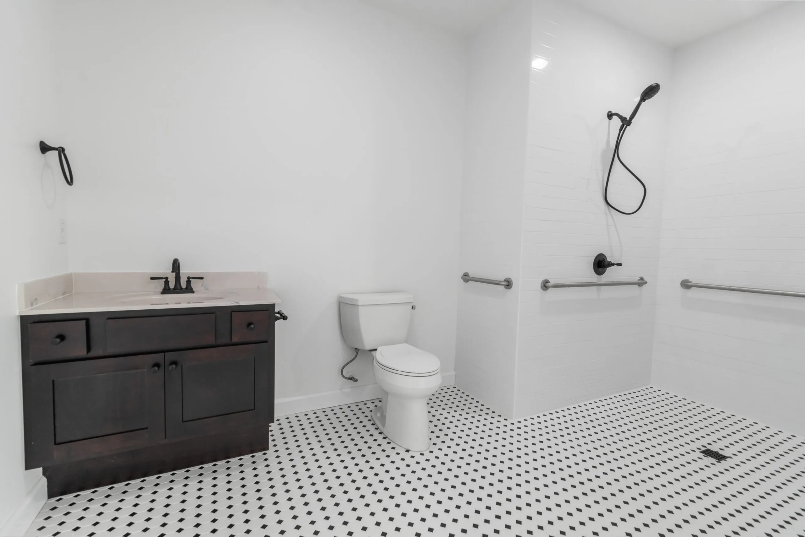 Accessible bathroom with roll-in shower and black-and-white tile in the Otterlea Home