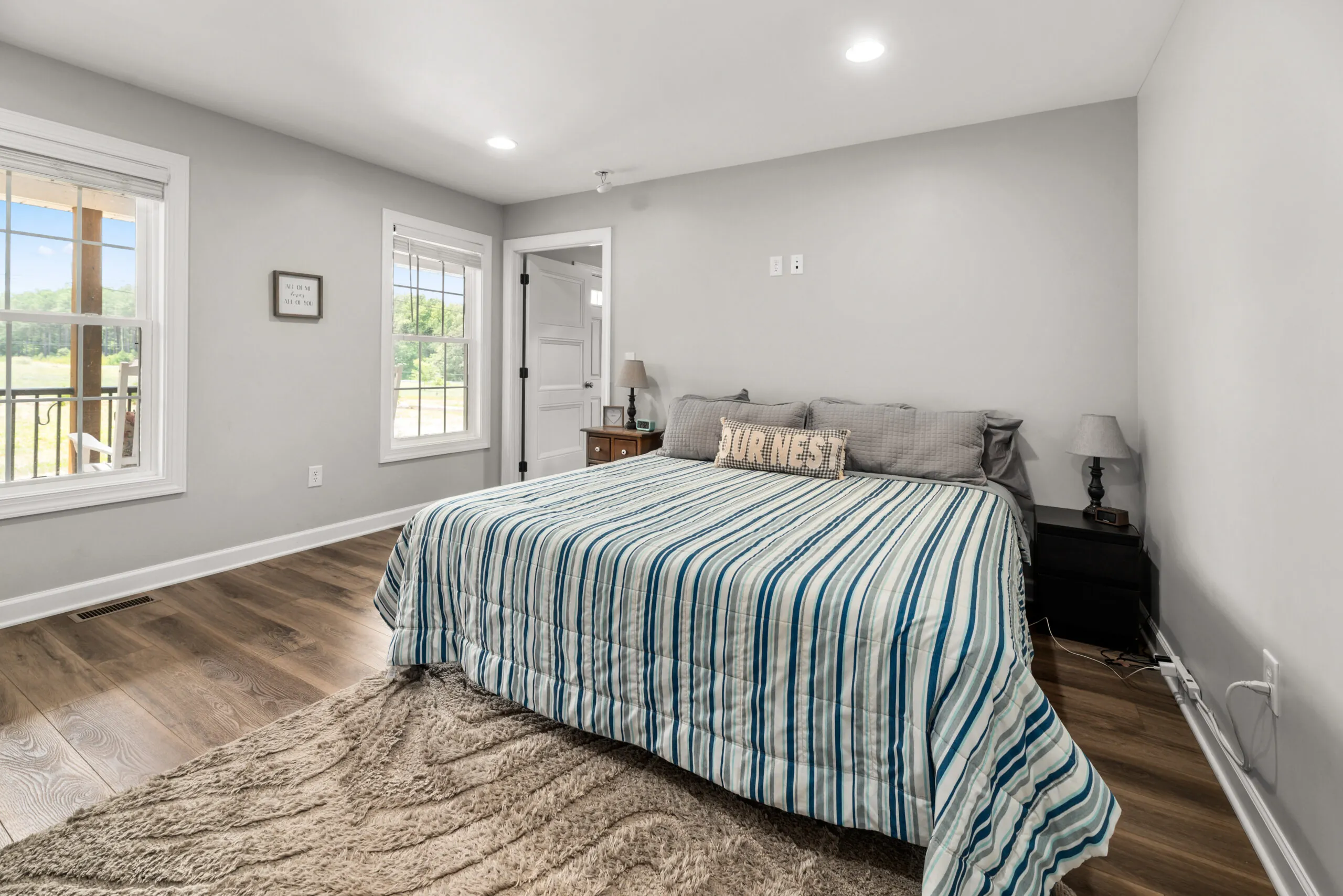 Primary bedroom with striped bedding and porch-view windows in the Timber Ridge Home
