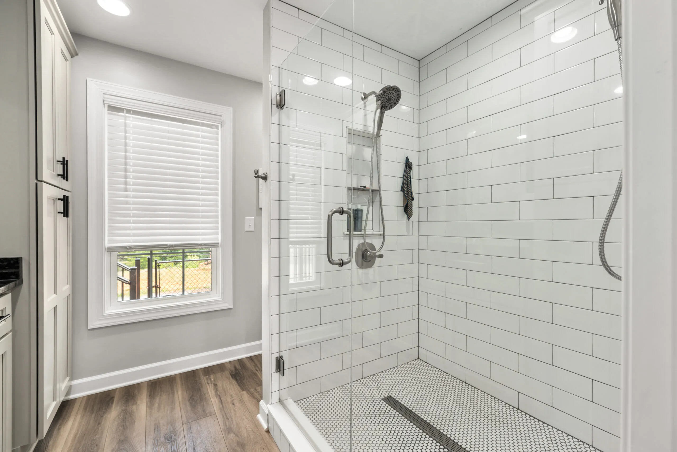 Primary bathroom glass-enclosed tile shower and window in the Timber Ridge Home