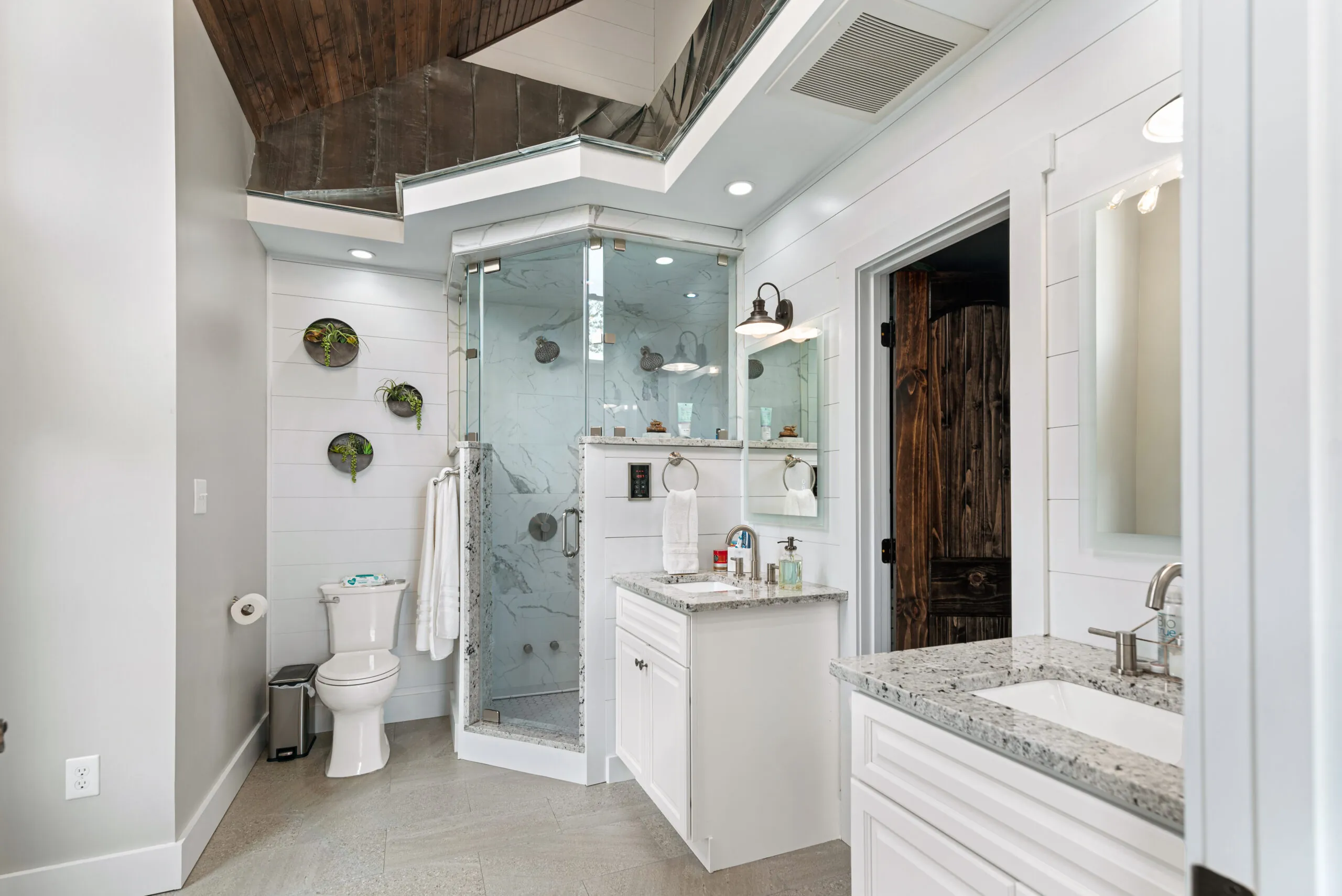 Primary bath with corner glass shower and granite vanities in the Lowry Home