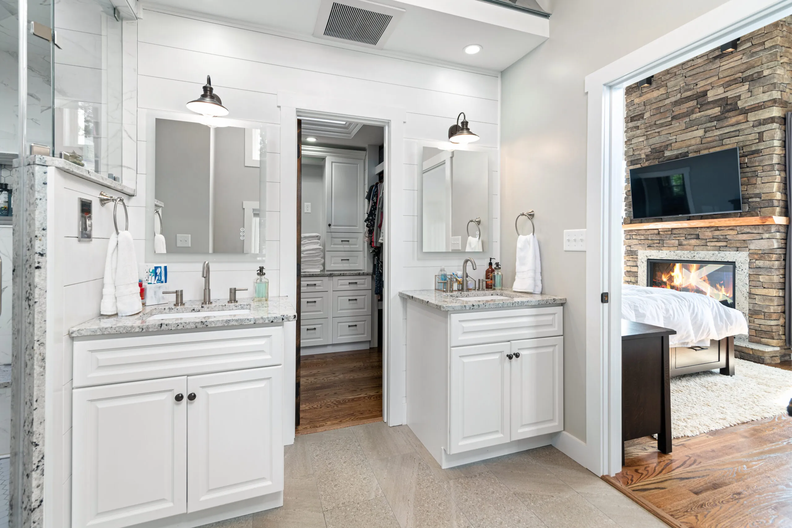 Primary bath vanities with view of the bedroom stone fireplace in the Lowry Home