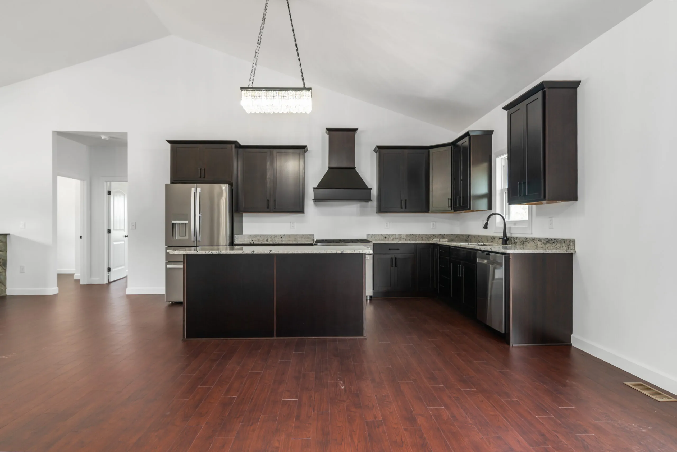 Open kitchen with dark cabinets and vaulted ceiling in the Otterlea Home