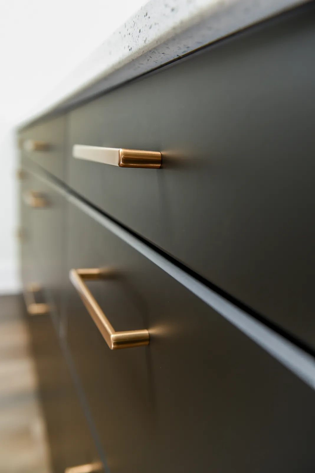 Close-up of brass pulls on dark kitchen cabinetry in the LynBrook Home
