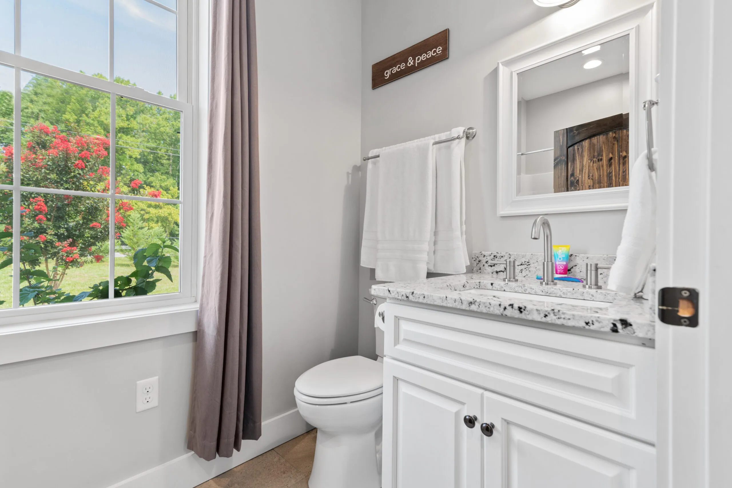 Half bath with white vanity, granite top and window in the Lowry Home