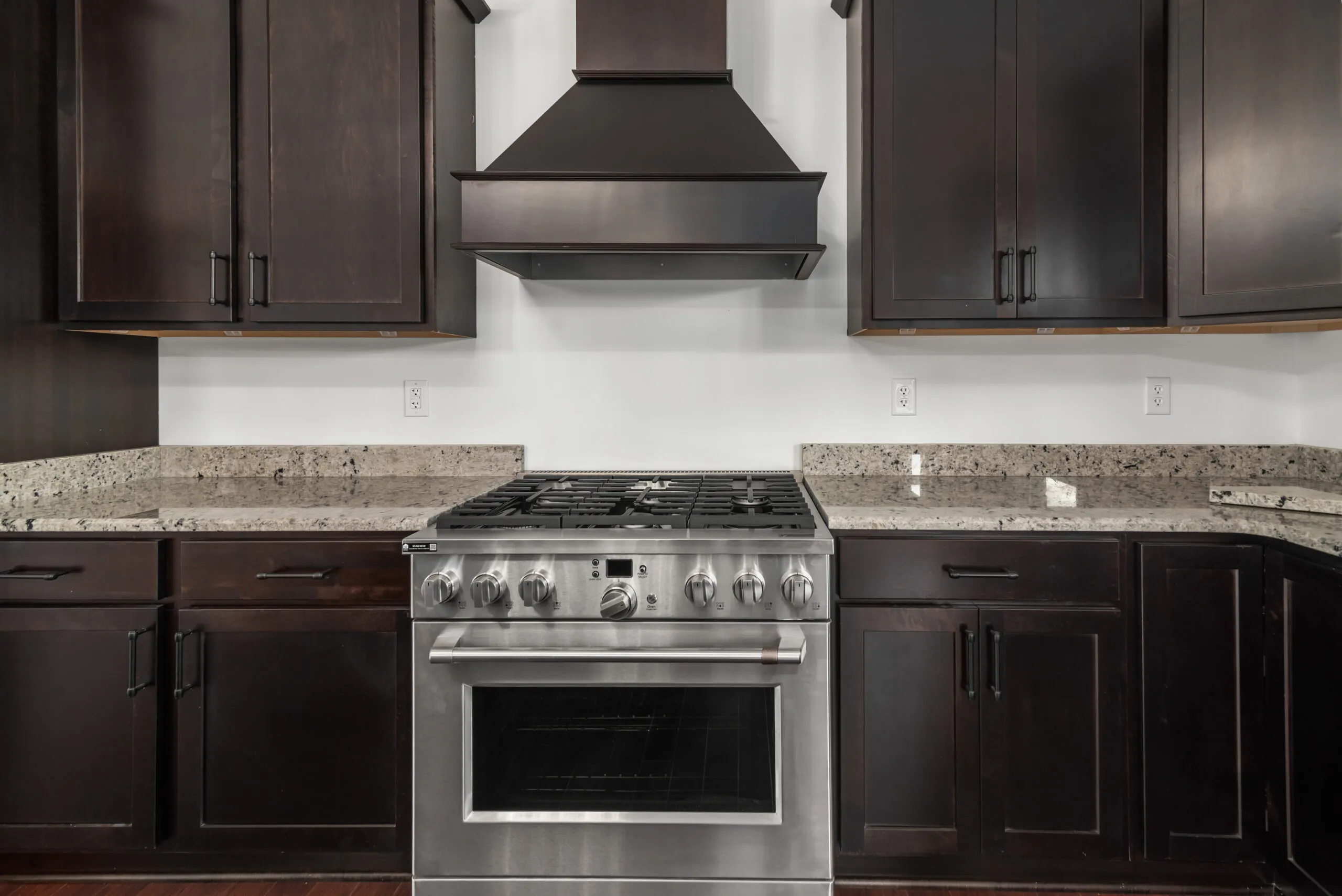 Dark cabinetry, granite counters and gas range in the kitchen of the Otterlea Home