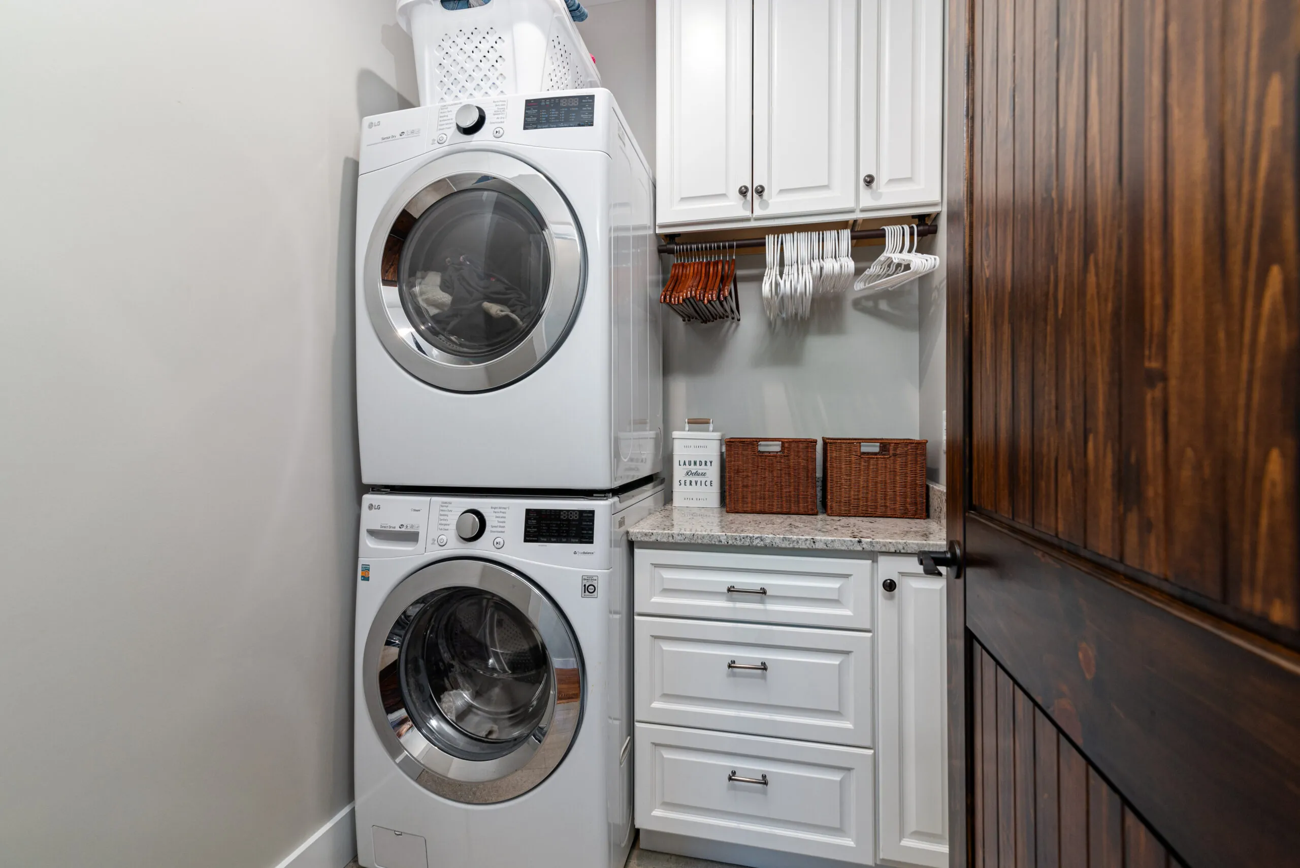 Laundry room with stacked washer and dryer and white cabinets in the Lowry Home