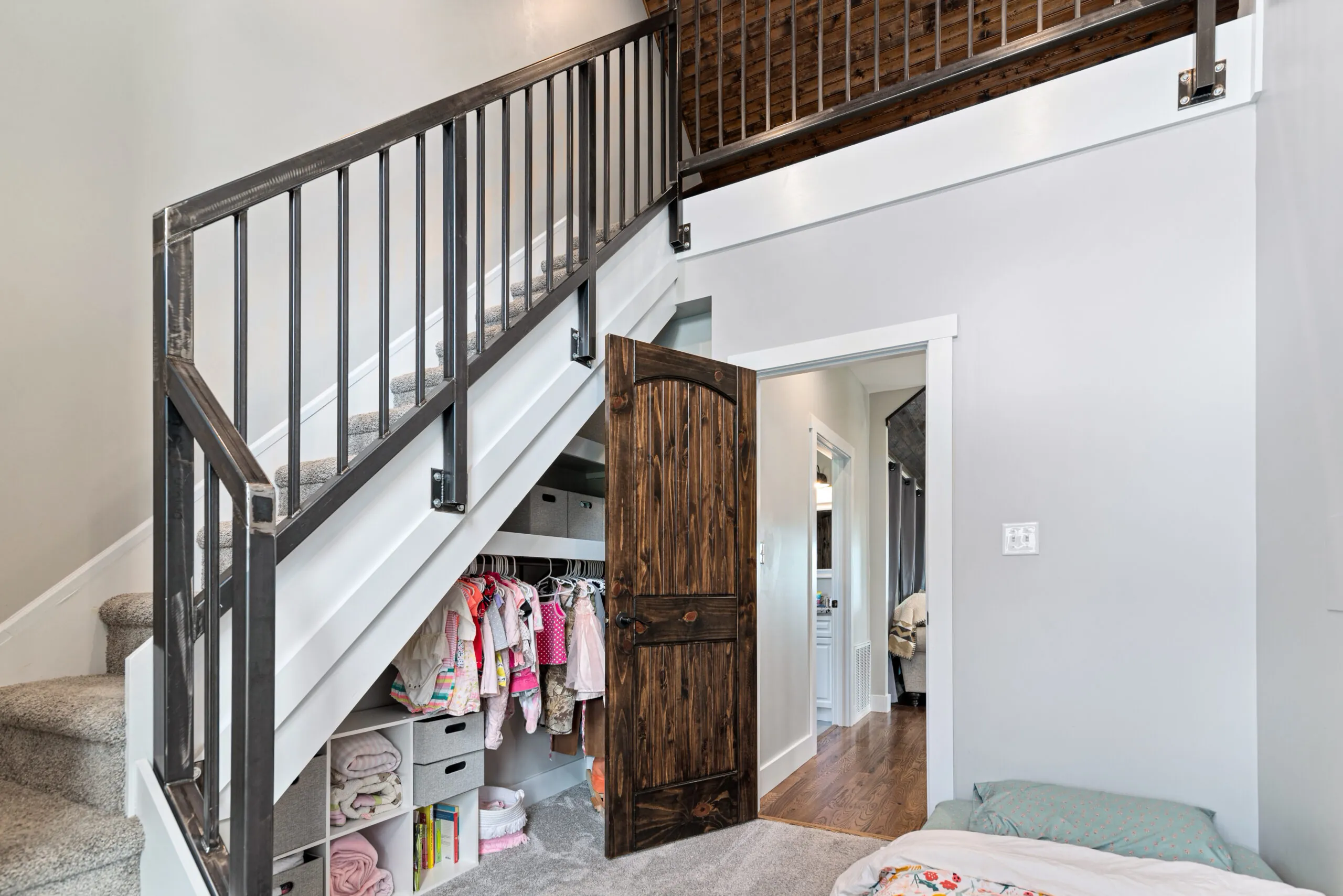 Under-stair closet with rustic wood door and open shelving in the Lowry Home