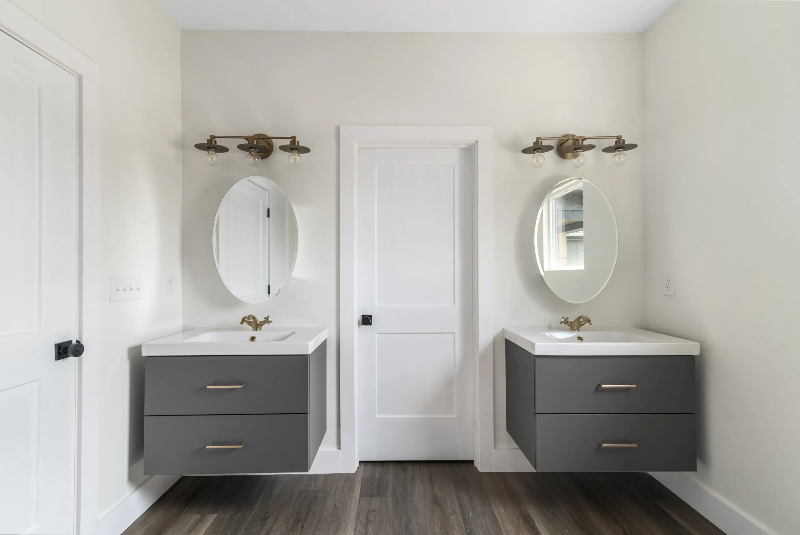 Primary bath with two floating gray vanities and oval mirrors in the LynBrook Home