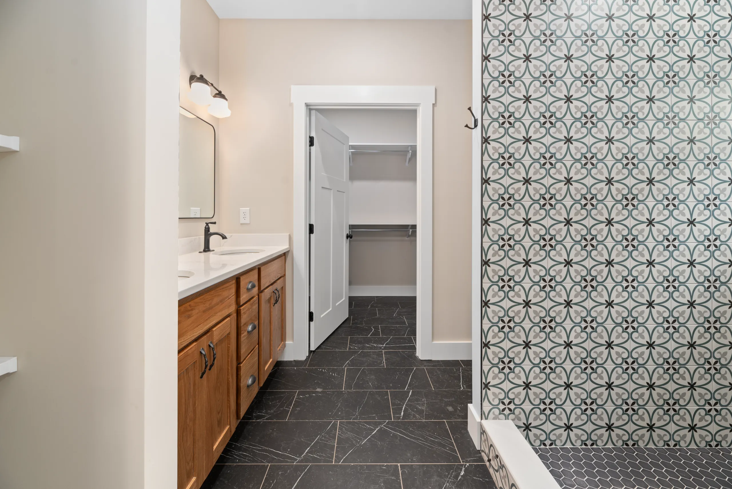 Primary bathroom with double vanity, tiled shower and walk-in closet in the Lake Crest Home