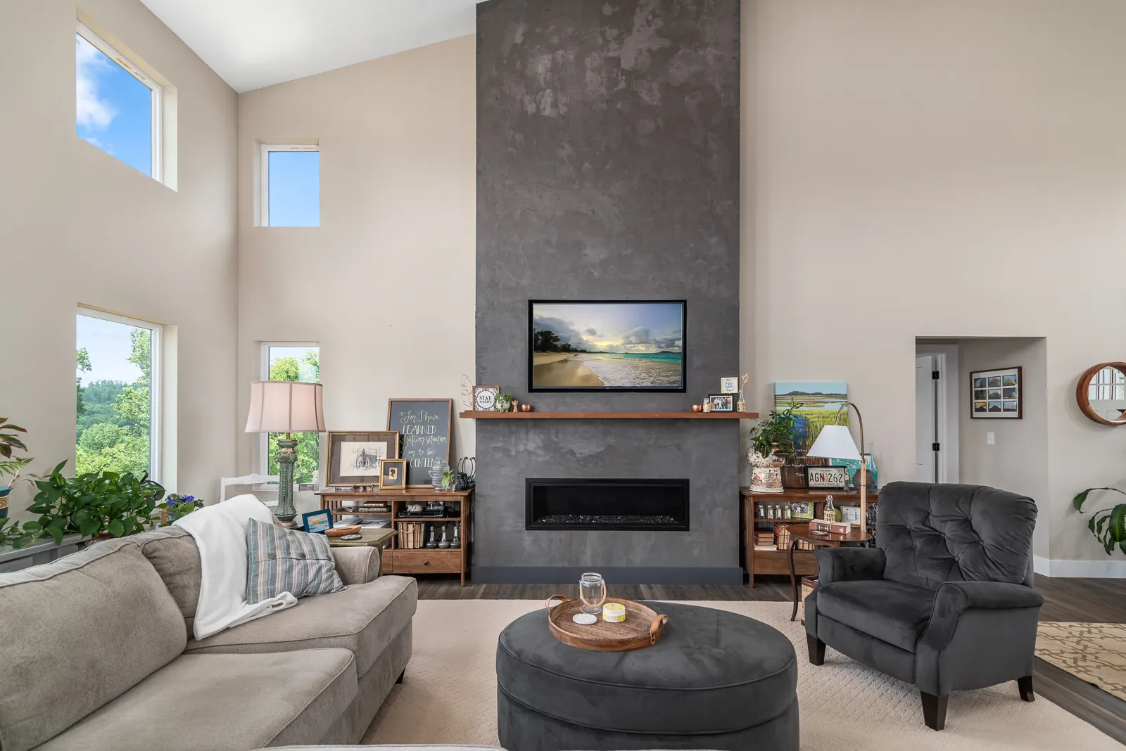 Living room with tall slate fireplace and large windows in the LynBrook Home