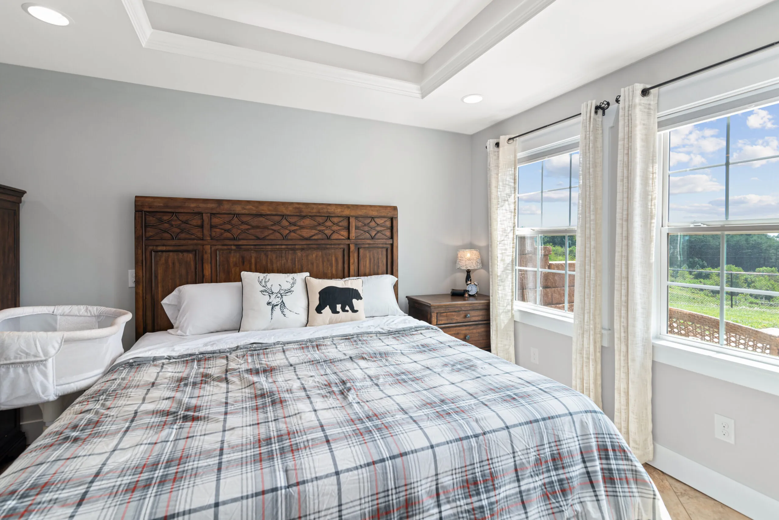 Bedroom with tray ceiling, wood headboard and plaid bedding in the Lowry Home