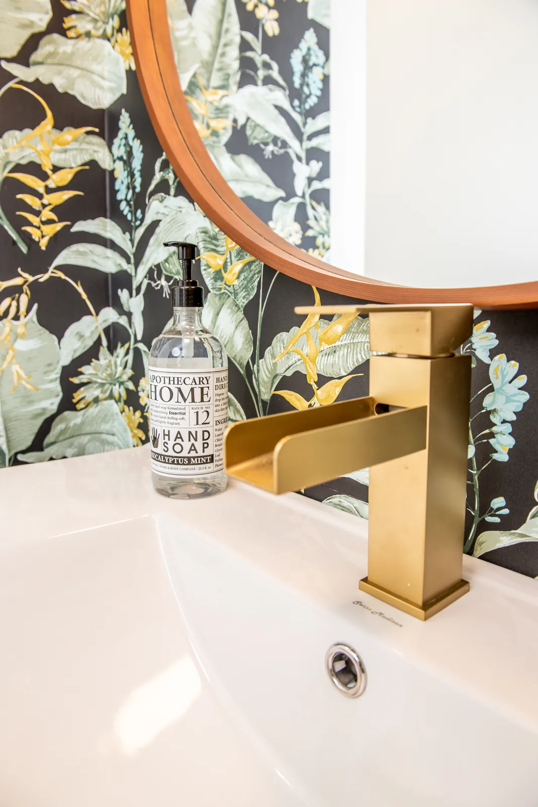 Brass waterfall faucet and botanical wallpaper in a LynBrook Home bathroom