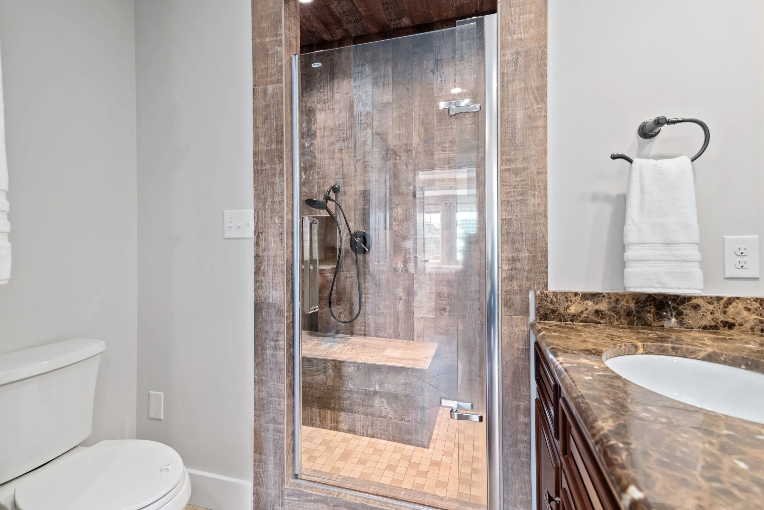 Walk-in tile shower with glass door and rustic wood trim in the Lowry Home